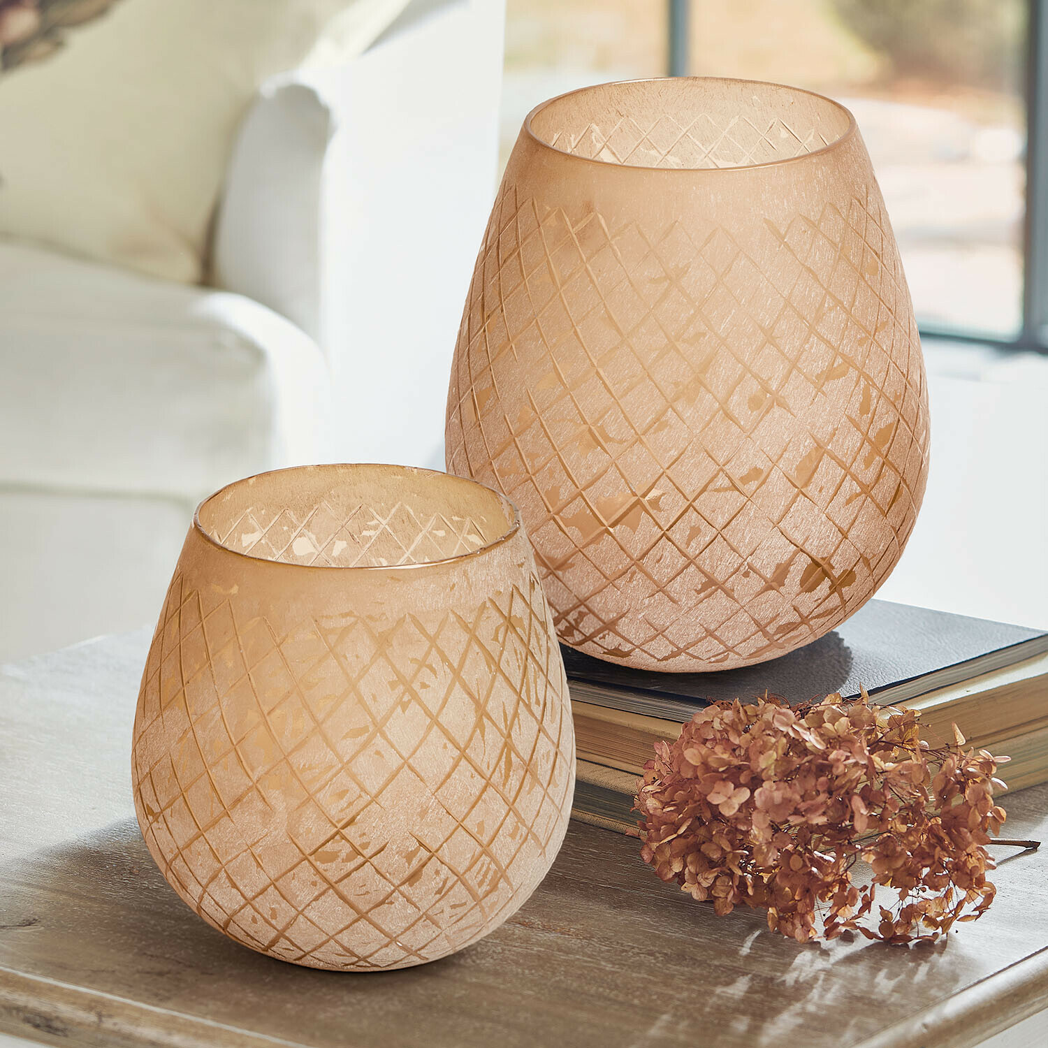 Windlicht set van 2 Méloriane Twee beige glazen windlichten met geometrisch patroon op houten tafel met gedroogde bloemen