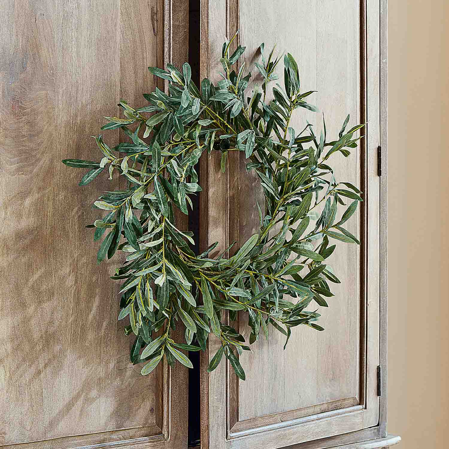 Decoratieve krans van groene bladeren aan houten deur, natuurlijke interieurdecoratie