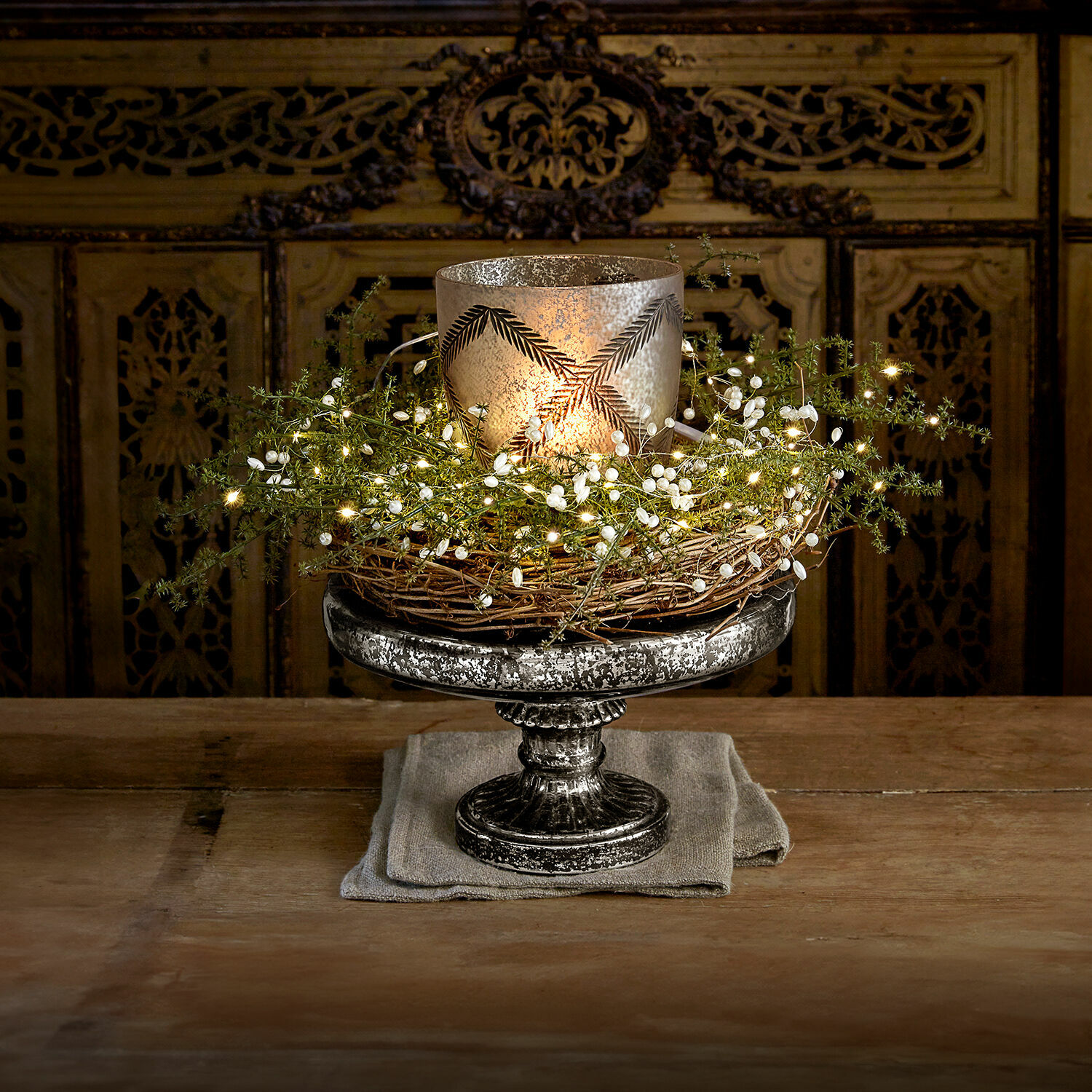 Etagère Incantesse Decoratieve zilverkleurige metalen kandelaar met wilgenkrans en LED-lichtjes op houten tafel