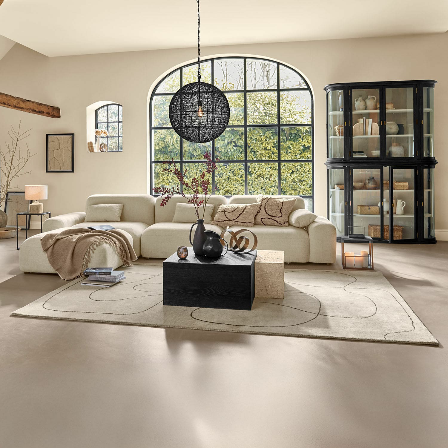 Vloerkleed Lavinois Ruime woonkamer met beige stoffen bank en zwarte houten salontafel op patroon vloerkleed