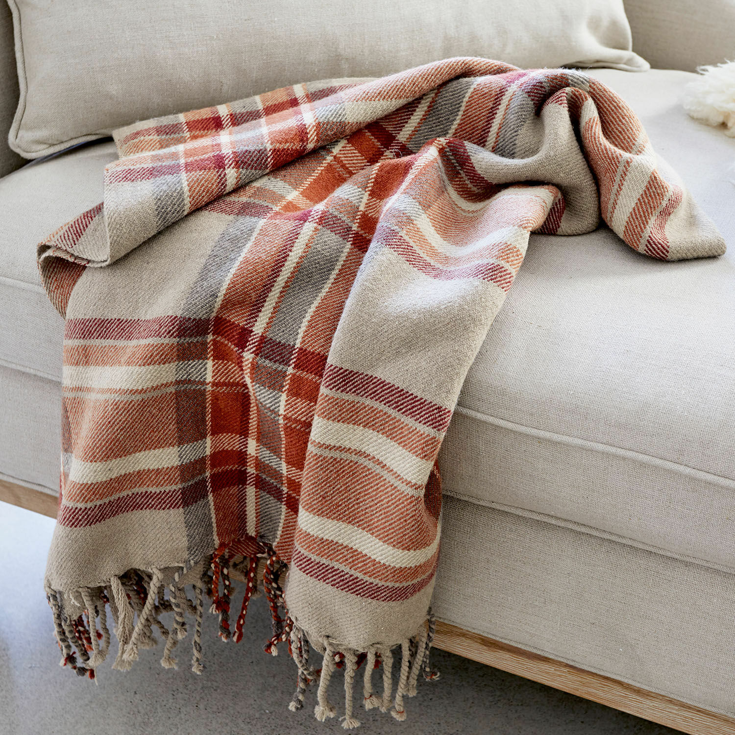 Plaid Tartan Zachte katoenen geruite deken in beige en rood op lichte bank, sfeervolle woonaccessoire