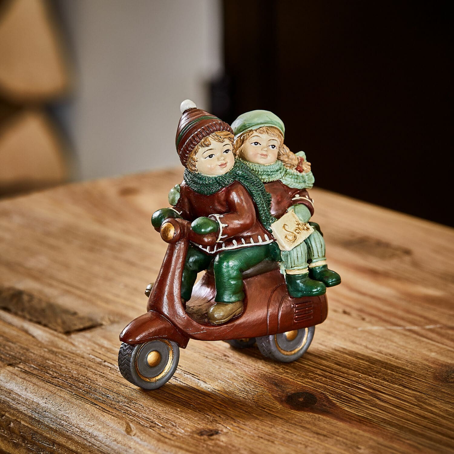 Figurine décorative Dariell Figurine d'enfants sur trottinette marron avec vêtements verts sur table en bois décoration hivernale