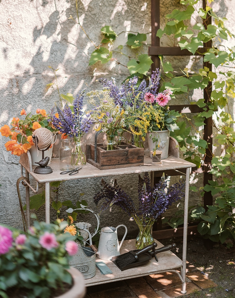 Metalen tuintafel met bloemen en tuingereedschap op een zonnige, schaduwrijke plek