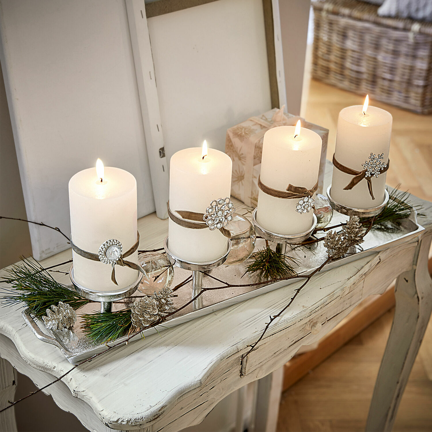 Kaarsenplateau Indila Decoratieve kandelaar met vier witte kaarsen en versieringen van dennenappels en takken op tafel