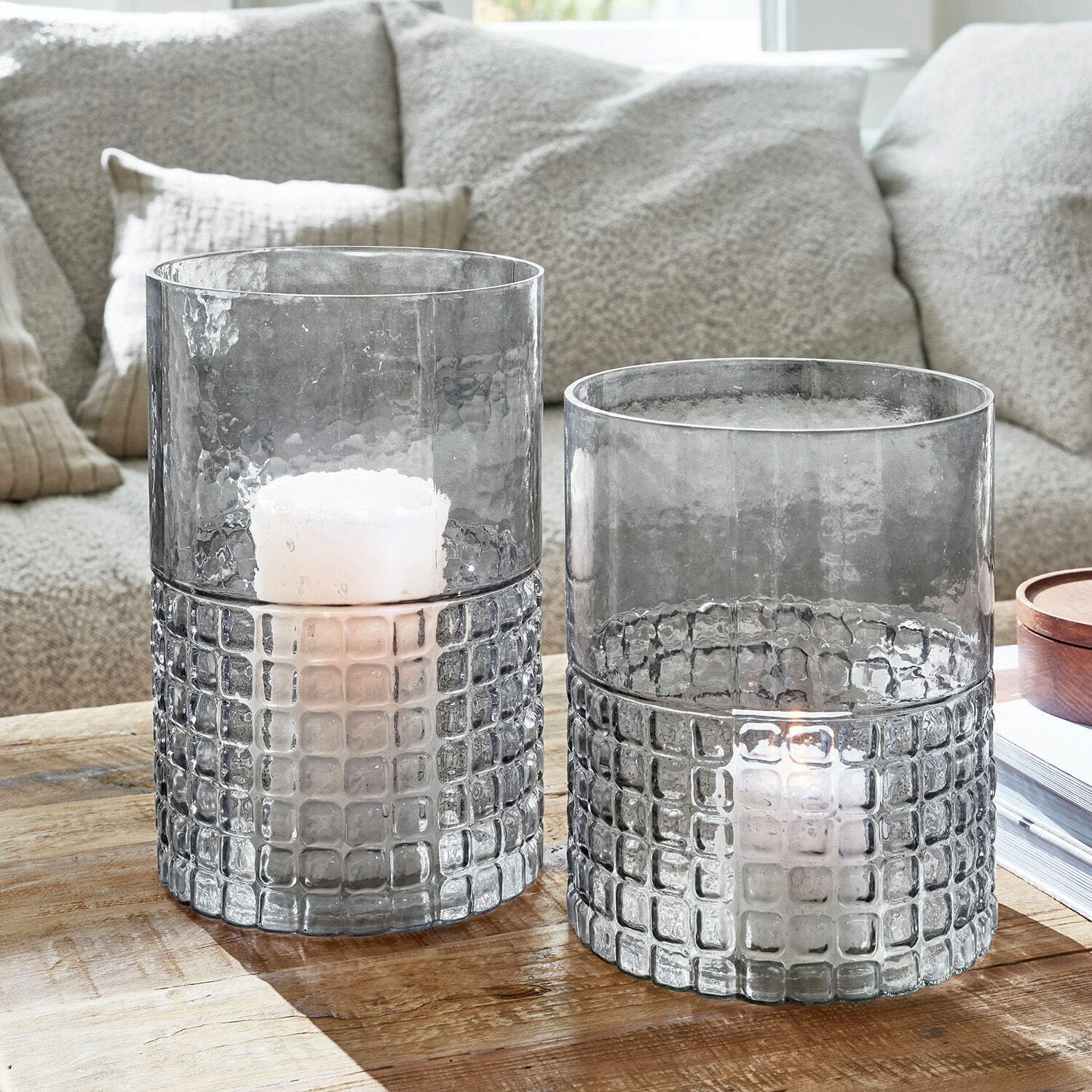 Lot de 2 lanternes Mandjes Photophores en verre gris texturé avec motif carré sur table en bois dans un salon