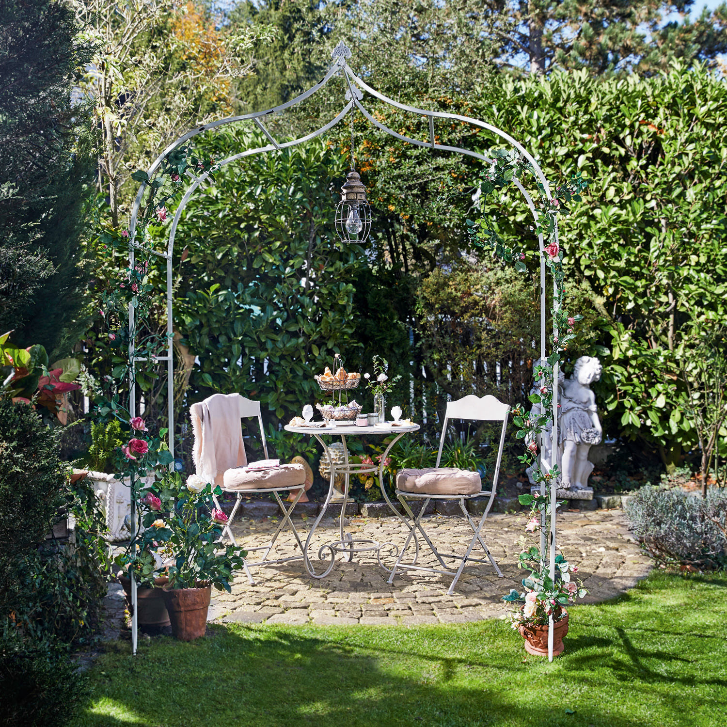 Arche à rosier Dimarus Arche de jardin en métal blanc avec fleurs roses et lampe suspendue, table et chaises sur patio en pierre