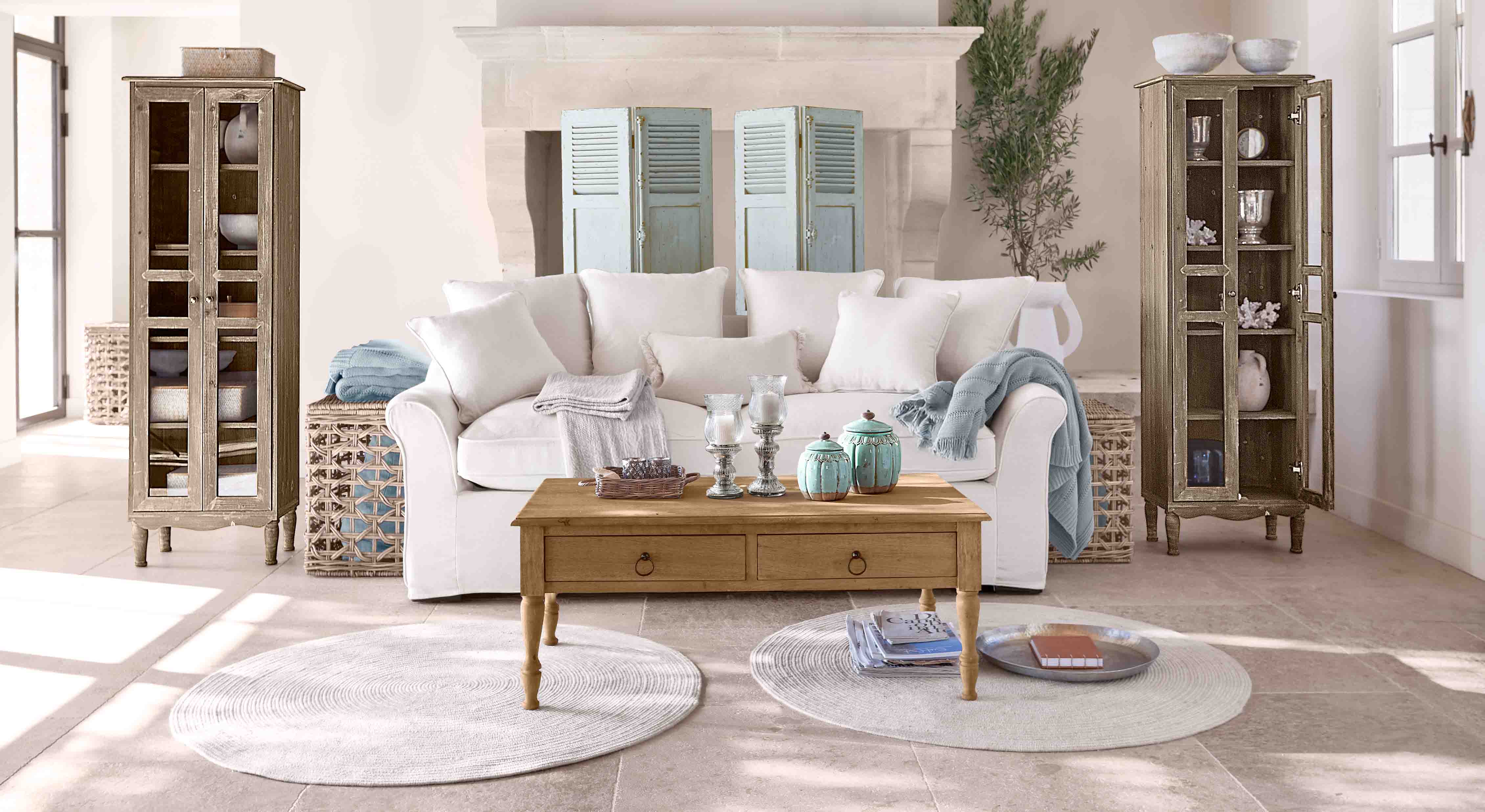 Gezellige woonkamer met witte bank, houten tafel en twee vintage houten vitrinekasten