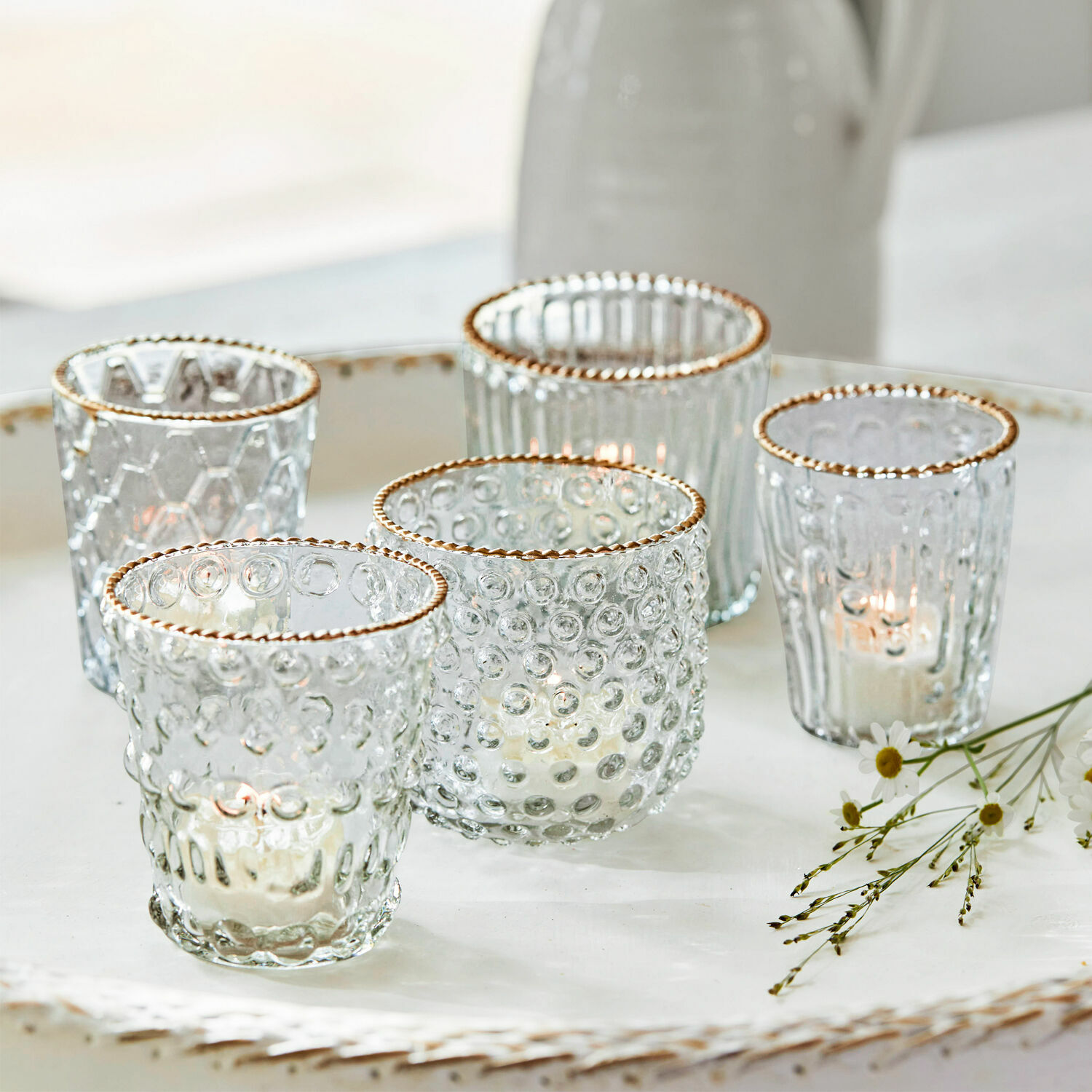 Lot de 5 photophores Jarnac Ensemble de cinq photophores en verre avec bord doré et texture, posés sur un plateau blanc décoratif