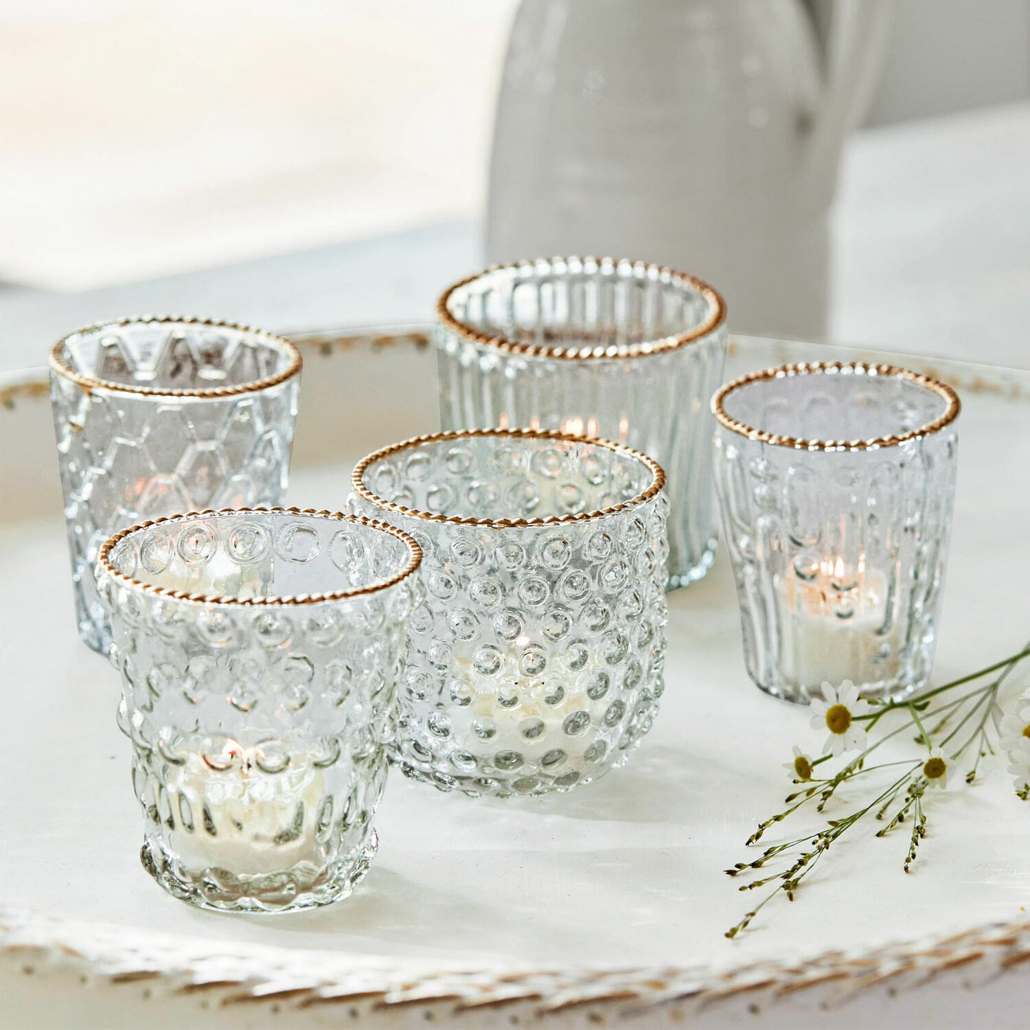 Windlicht set van 5 Jarnac Set van vijf glazen theelichthouders met gouden rand en structuur op een wit decoratief dienblad