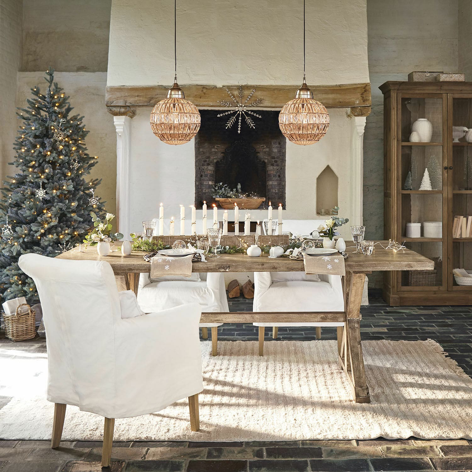 Table Dolignon Table en bois rustique avec chaises blanches et décoration de Noël dans un salon chaleureux avec cheminée