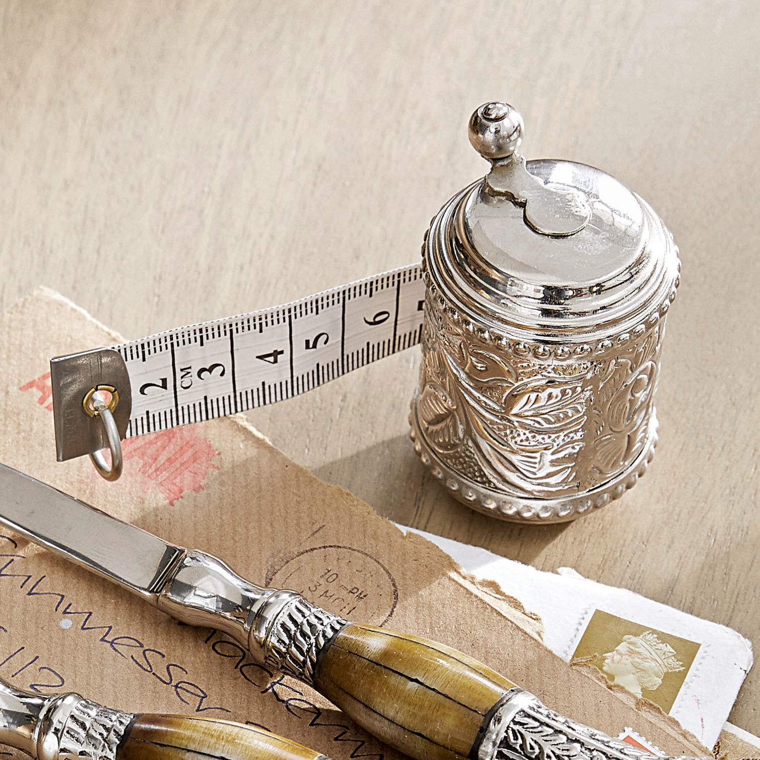 Meetlint Mètre Zilverkleurige metalen meetlint met decoratief patroon en witte meetband op houten tafel