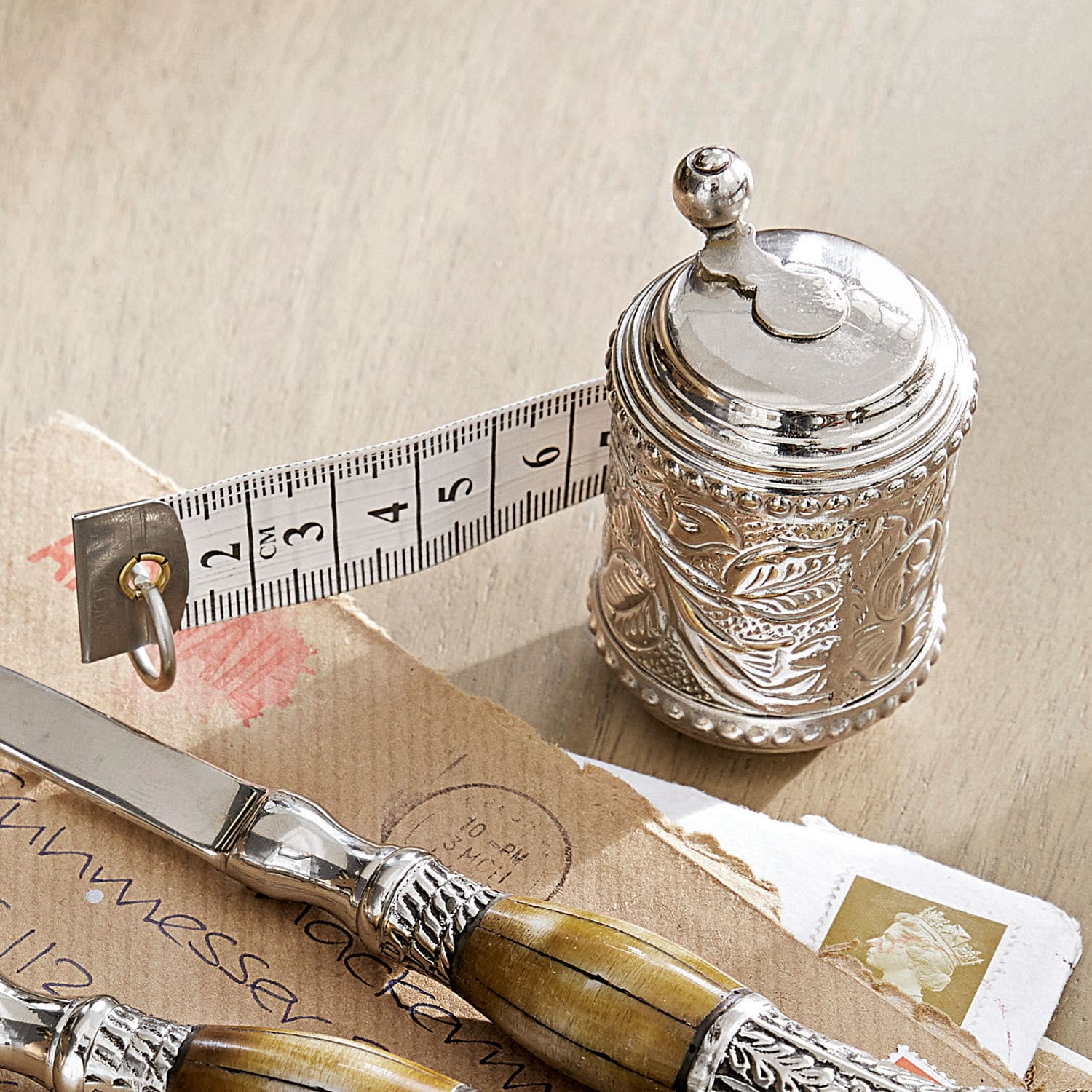 Meetlint Mètre Zilverkleurige metalen meetlint met decoratief patroon en witte meetband op houten tafel