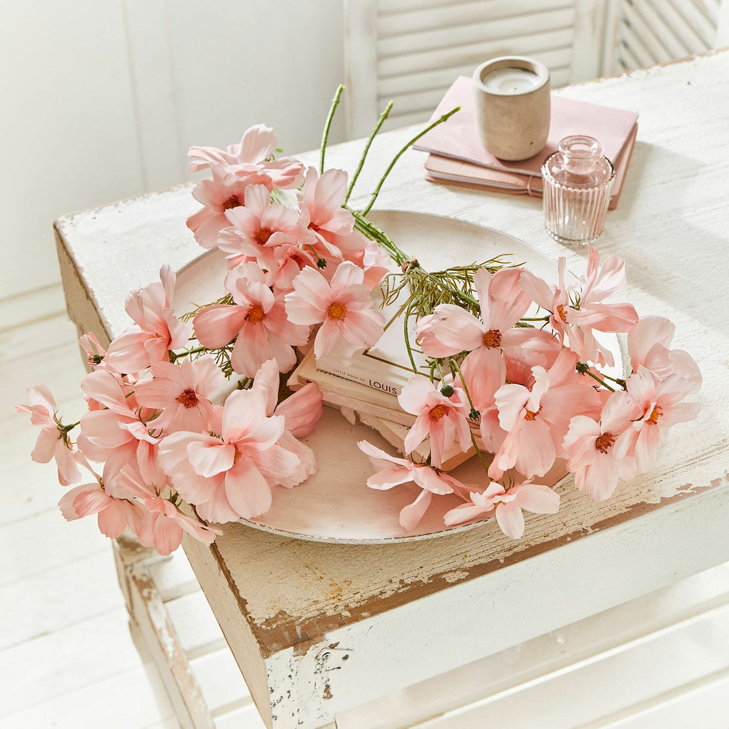 Bouquet décoratif Tilla Fleurs décoratives roses délicates posées sur une table en bois blanc vieilli pour décoration intérieure.