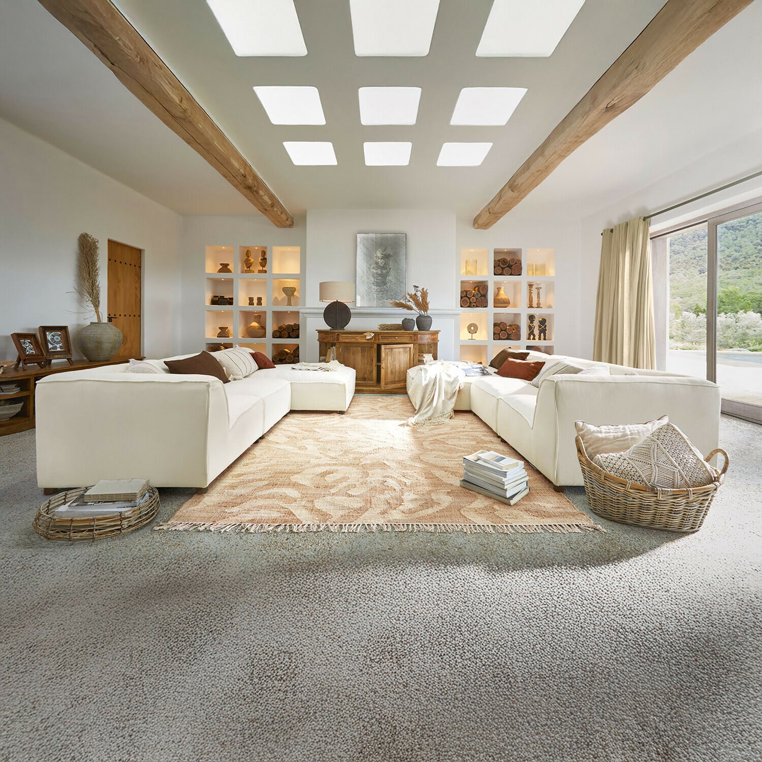 Canapé McLean Salon spacieux avec canapé blanc, poutres en bois, décorations naturelles, tapis beige et grande fenêtre lumineuse