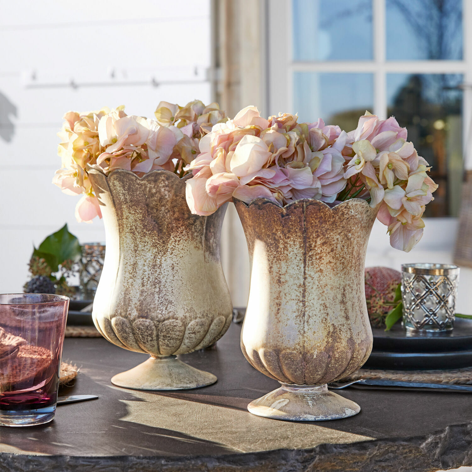 Vaas set van 2 Wilgard Twee beige-bruin keramische vazen met roze bloemen op een tuintafel