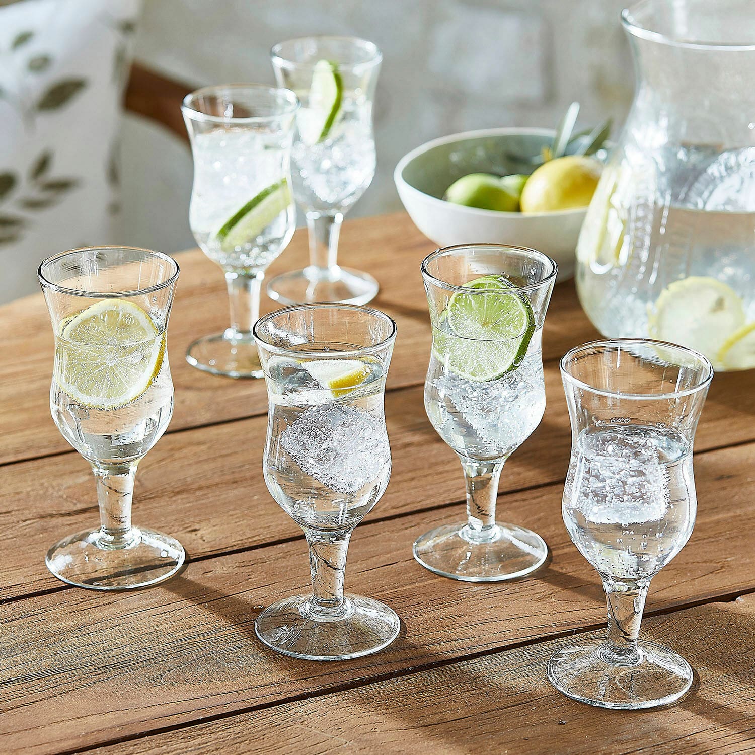 Lot de 6 verres Gaëtane Ensemble de six verres transparents avec eau, glaçons et tranches de citron sur table en bois