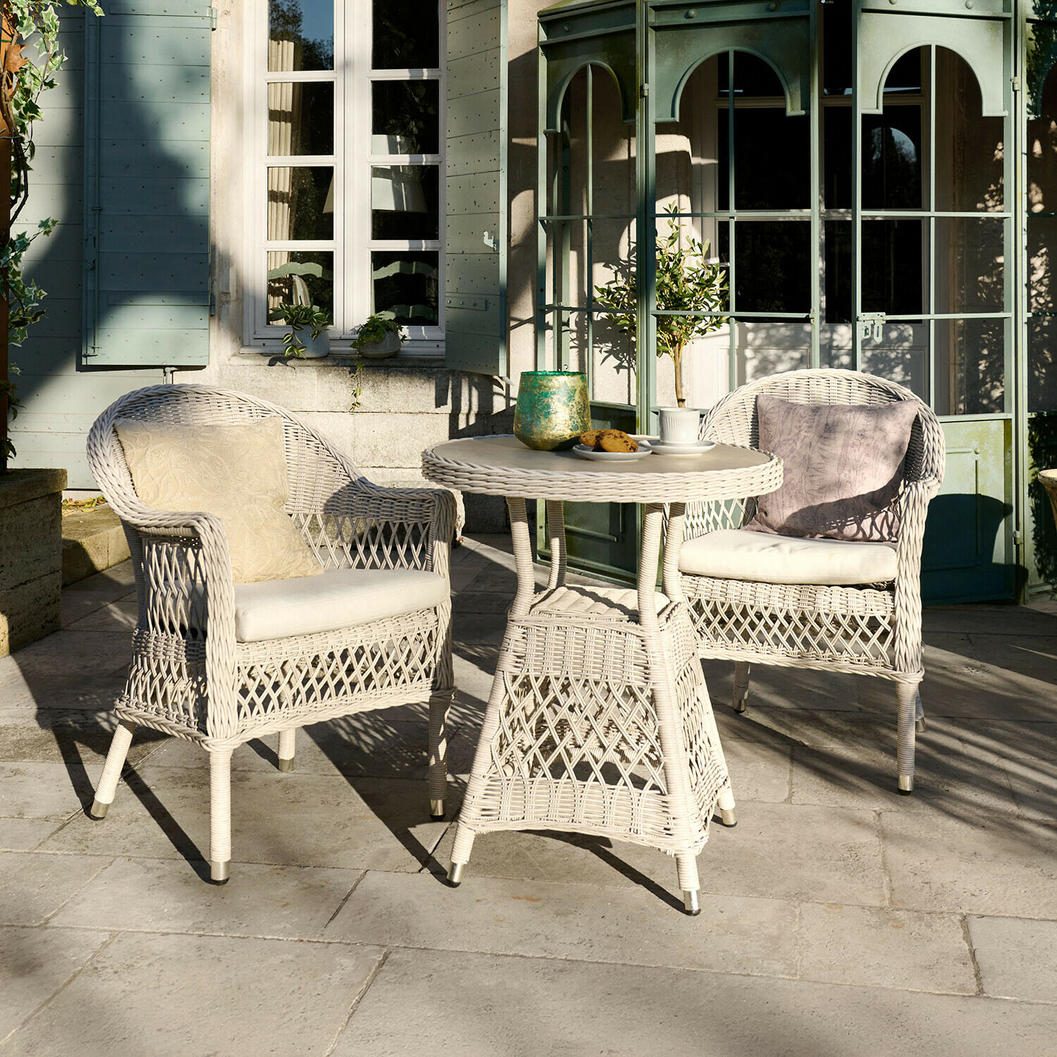 Tuinmeubelset van wit rattan met kussens, tafel en twee stoelen op terras