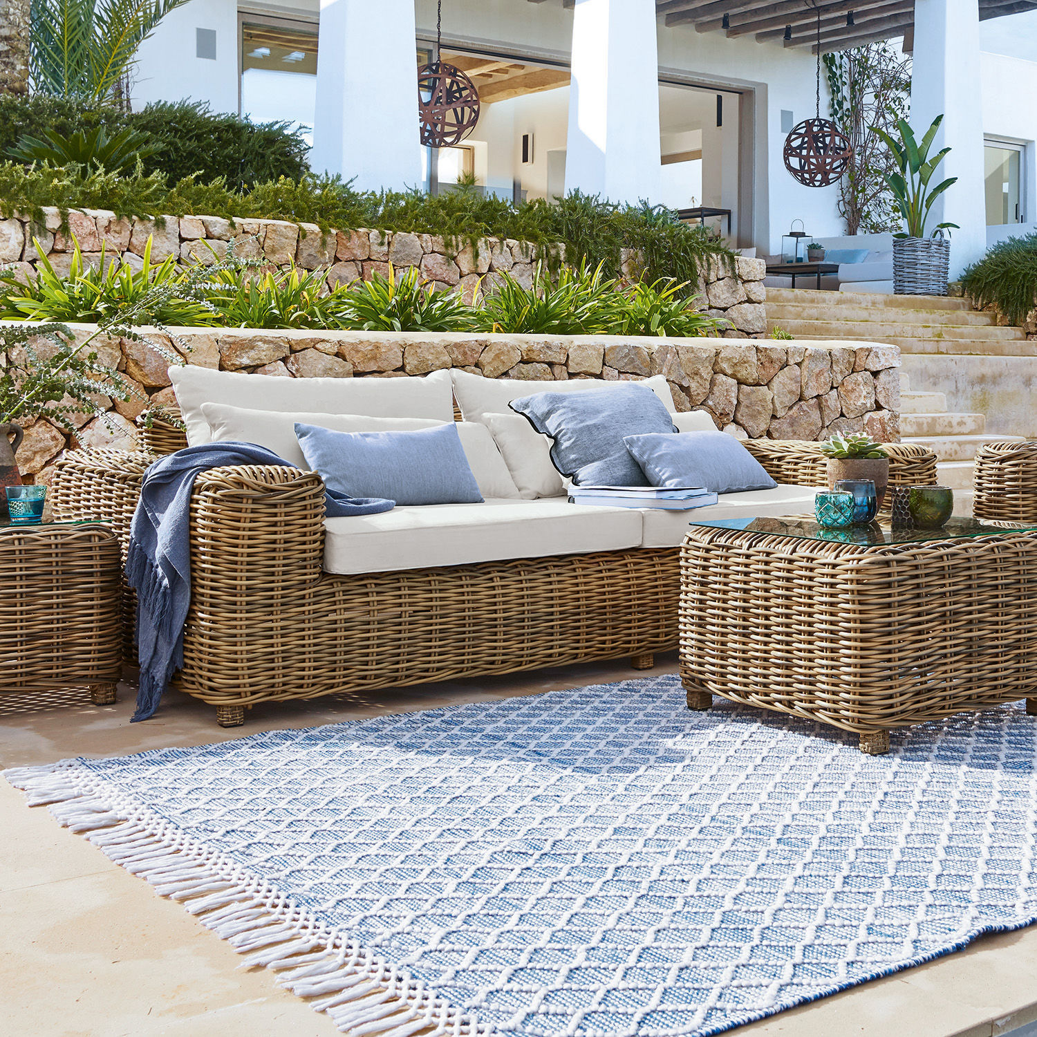 Bank Camas Tuinmeubelset van natuurlijk rattan met crèmekleurige kussens en blauw patroon vloerkleed