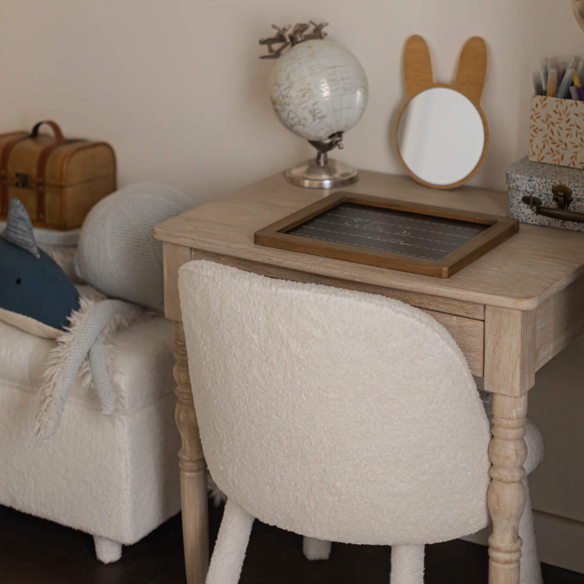 Bureau en bois clair avec chaise beige en tissu doux dans une chambre d'enfant chaleureuse