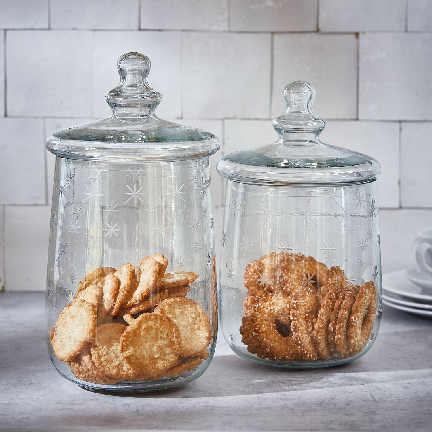 Lot de 2 bocaux en verre Valerico Deux bocaux en verre transparent avec couvercles, décorés d'étoiles, contenant des biscuits