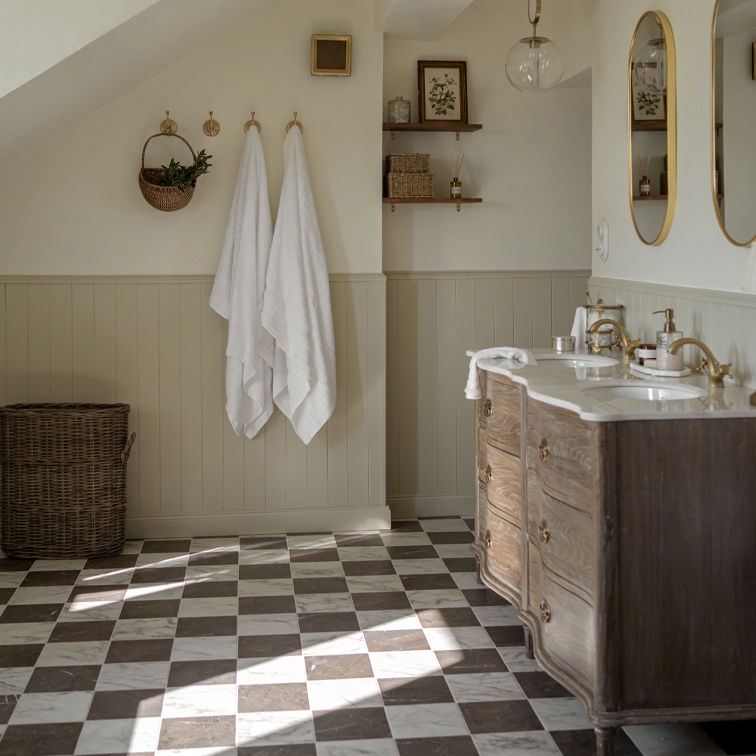 Salle de bain avec sol en marbre à carreaux, meuble en bois et serviettes blanches accrochées