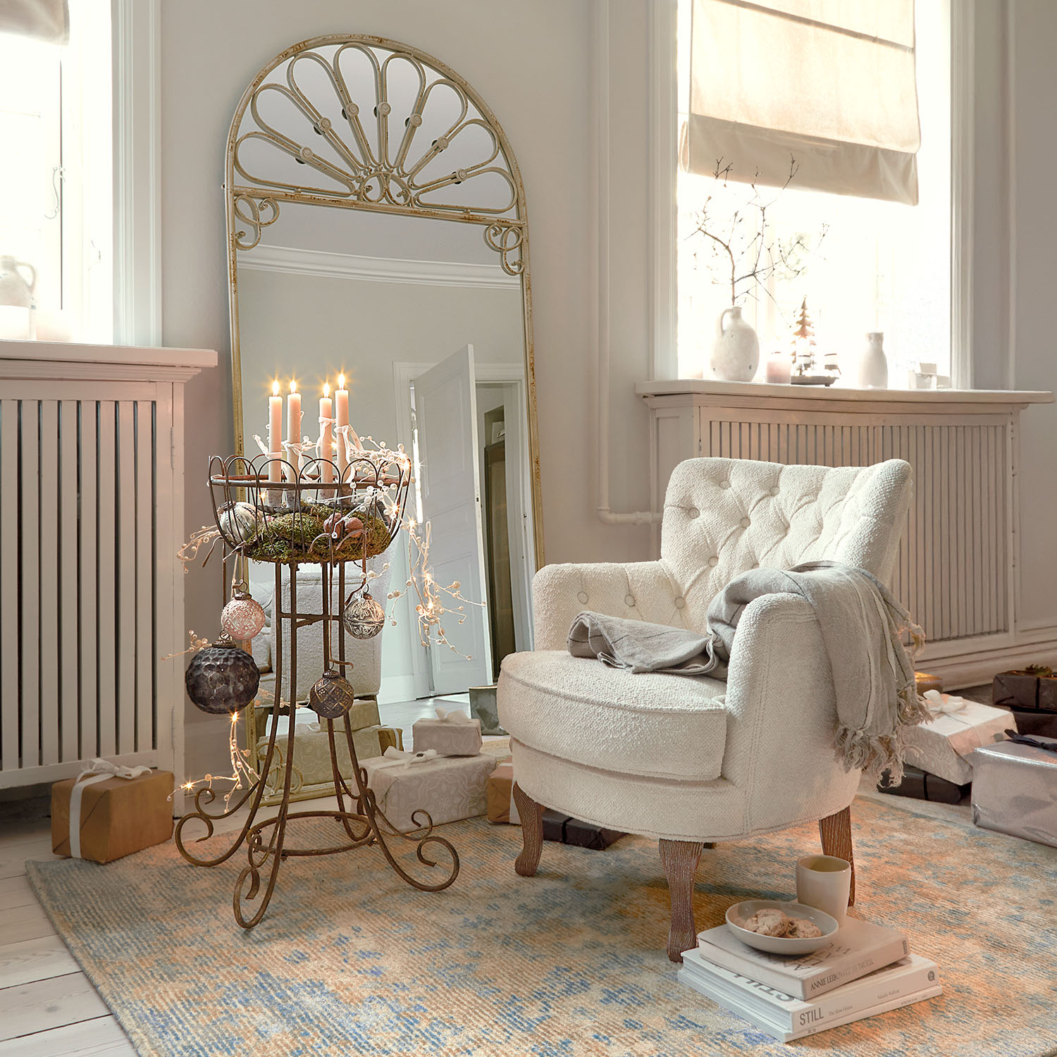 Gezellige witte bouclé fauteuil met houten poten in lichte woonkamer met feestelijke decoratie