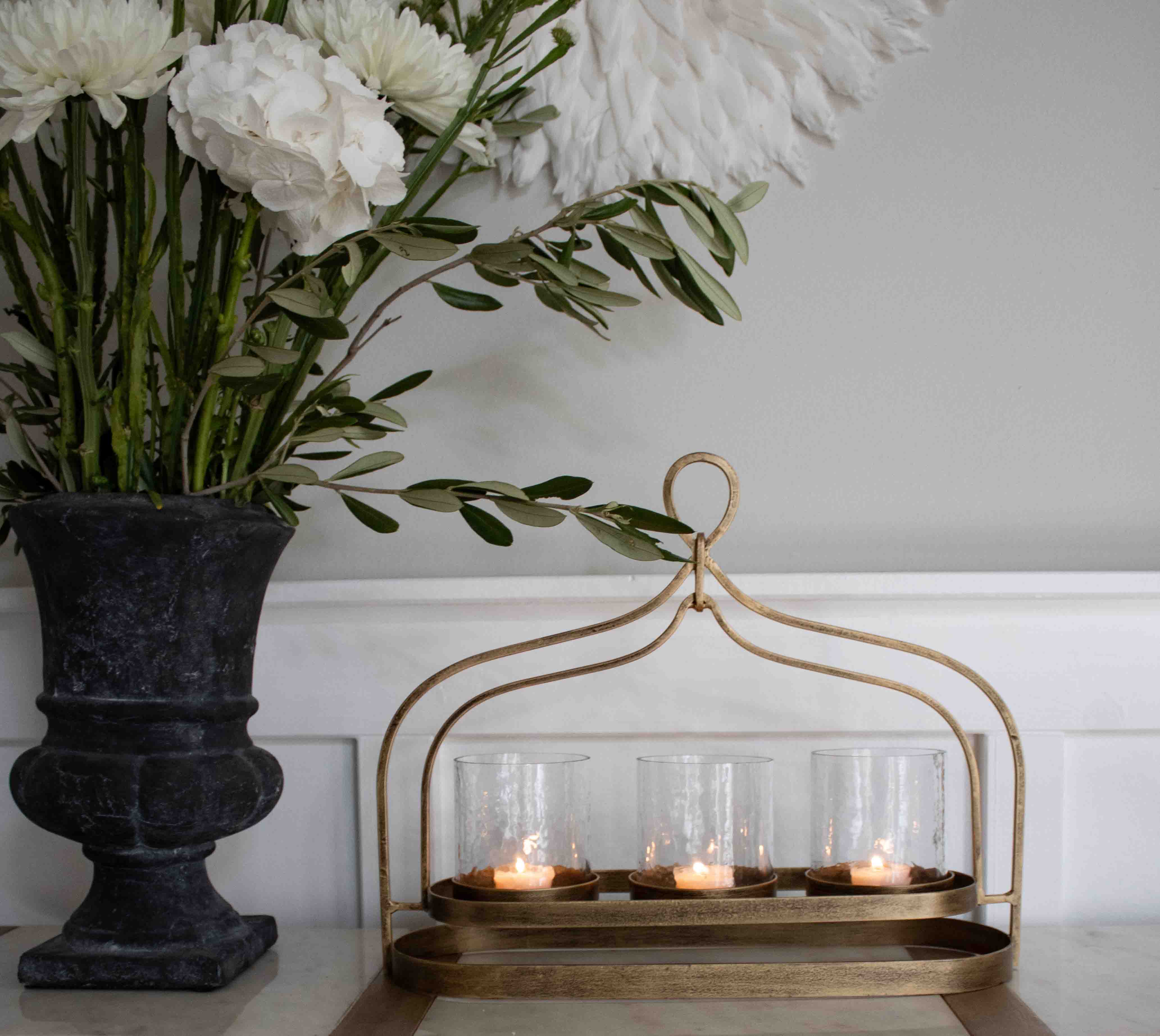 Gouden metalen kandelaar met drie glazen houdertjes voor theelichtjes op een decoratieve tafel