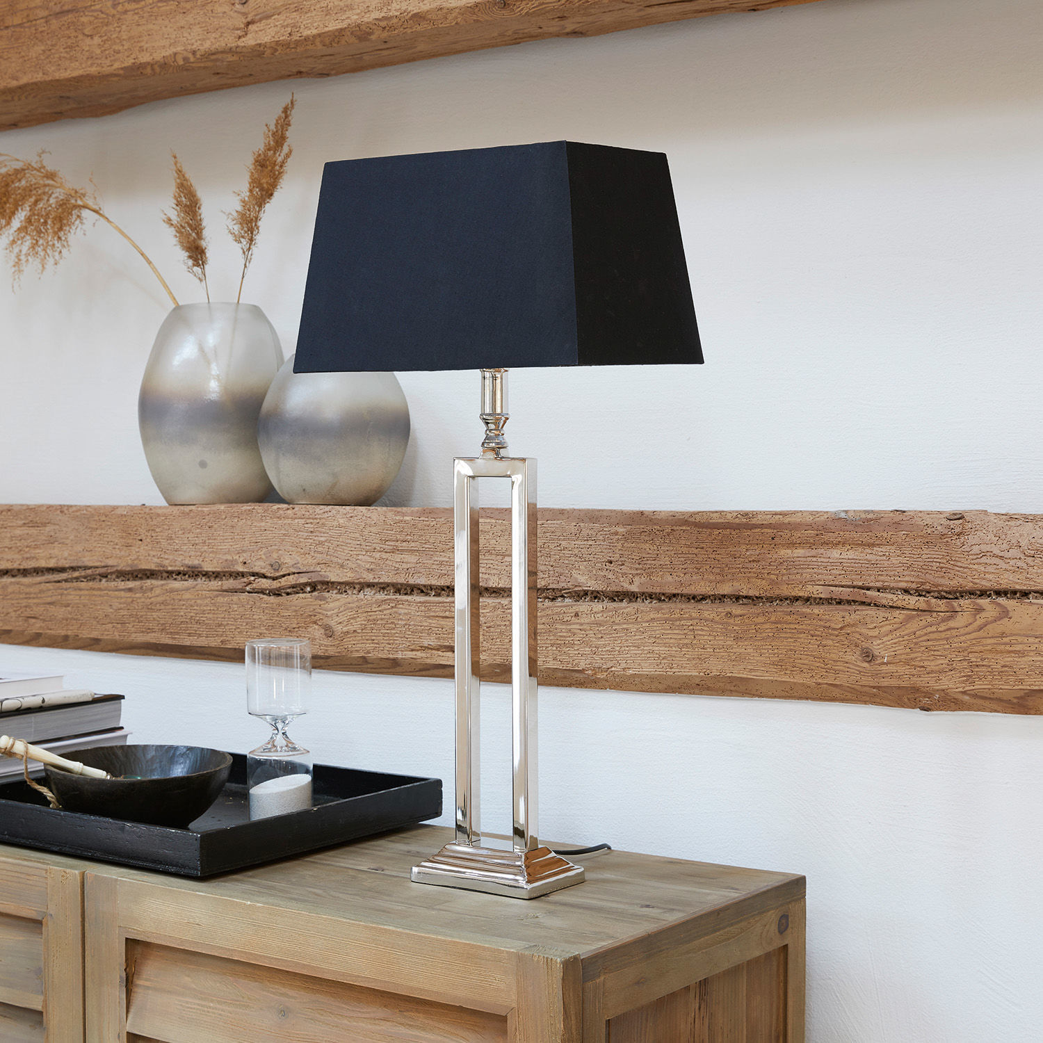 Tafellamp Kinshaa Elegante tafellamp met metalen voet en zwarte kap op licht houten kastje