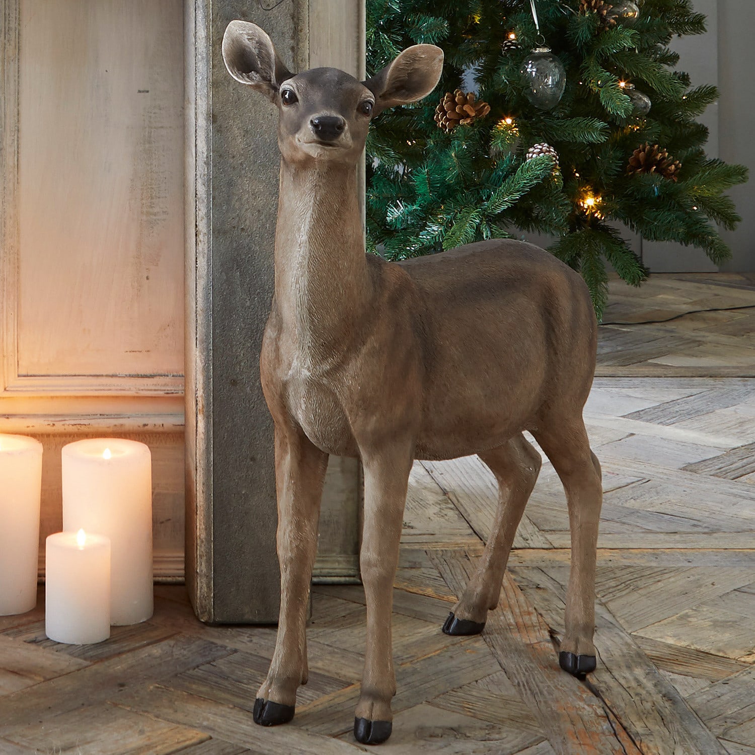 Biche Ruud Figurine décorative de cerf marron devant un sapin de Noël illuminé et des bougies
