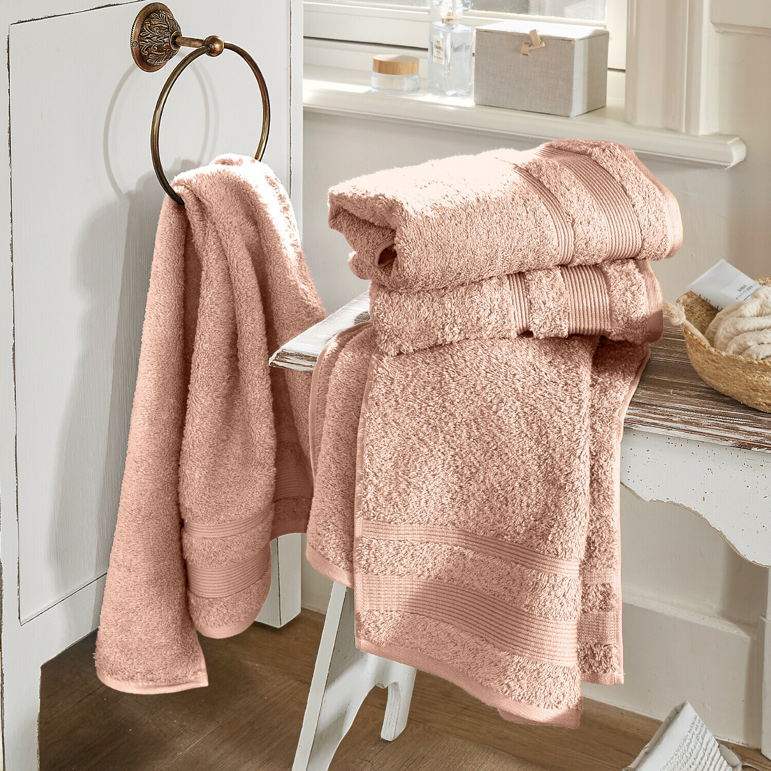 Roze katoenen badhanddoeken op wit meubel in lichte badkamer, zacht en absorberend