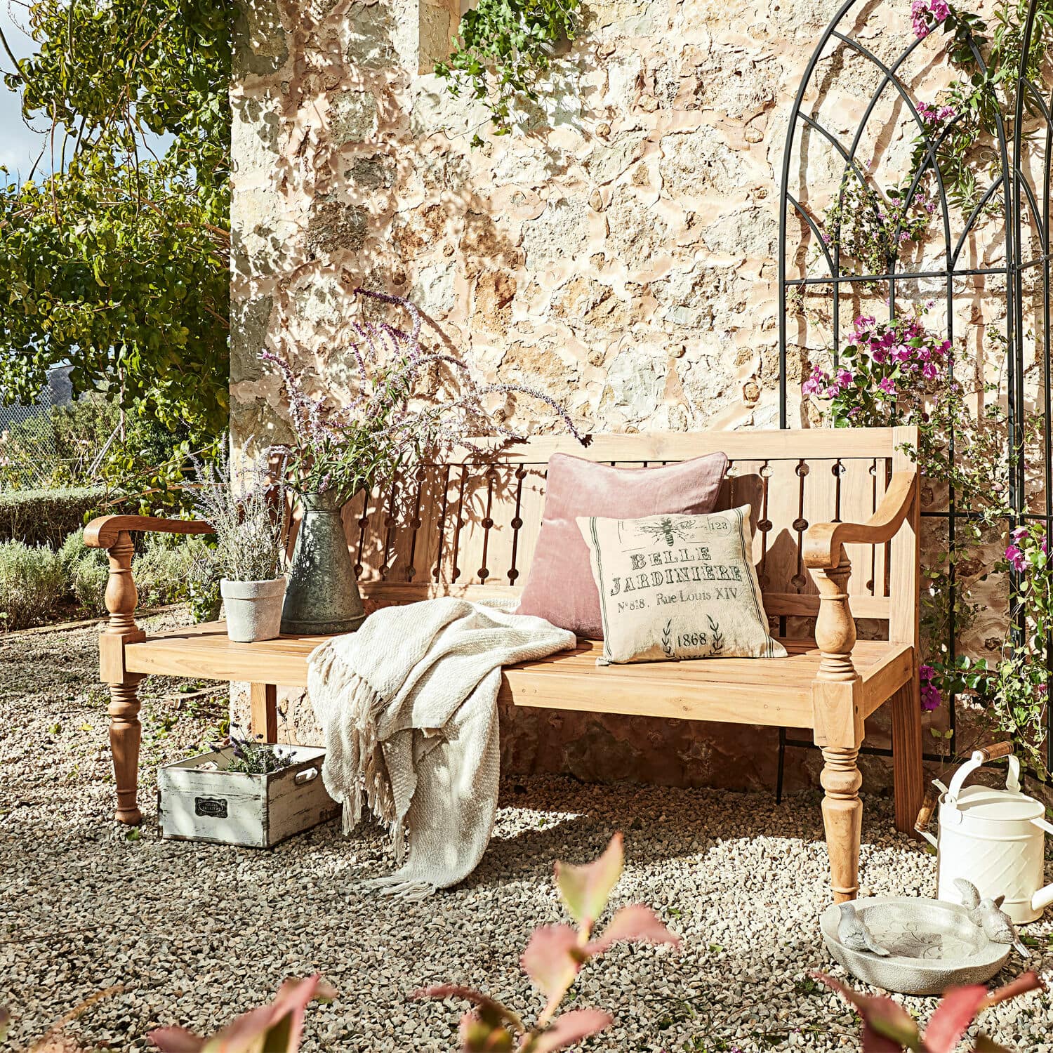 Bank Loudoun Houten tuinbank met kussens en deken op grindterras met planten en decoraties
