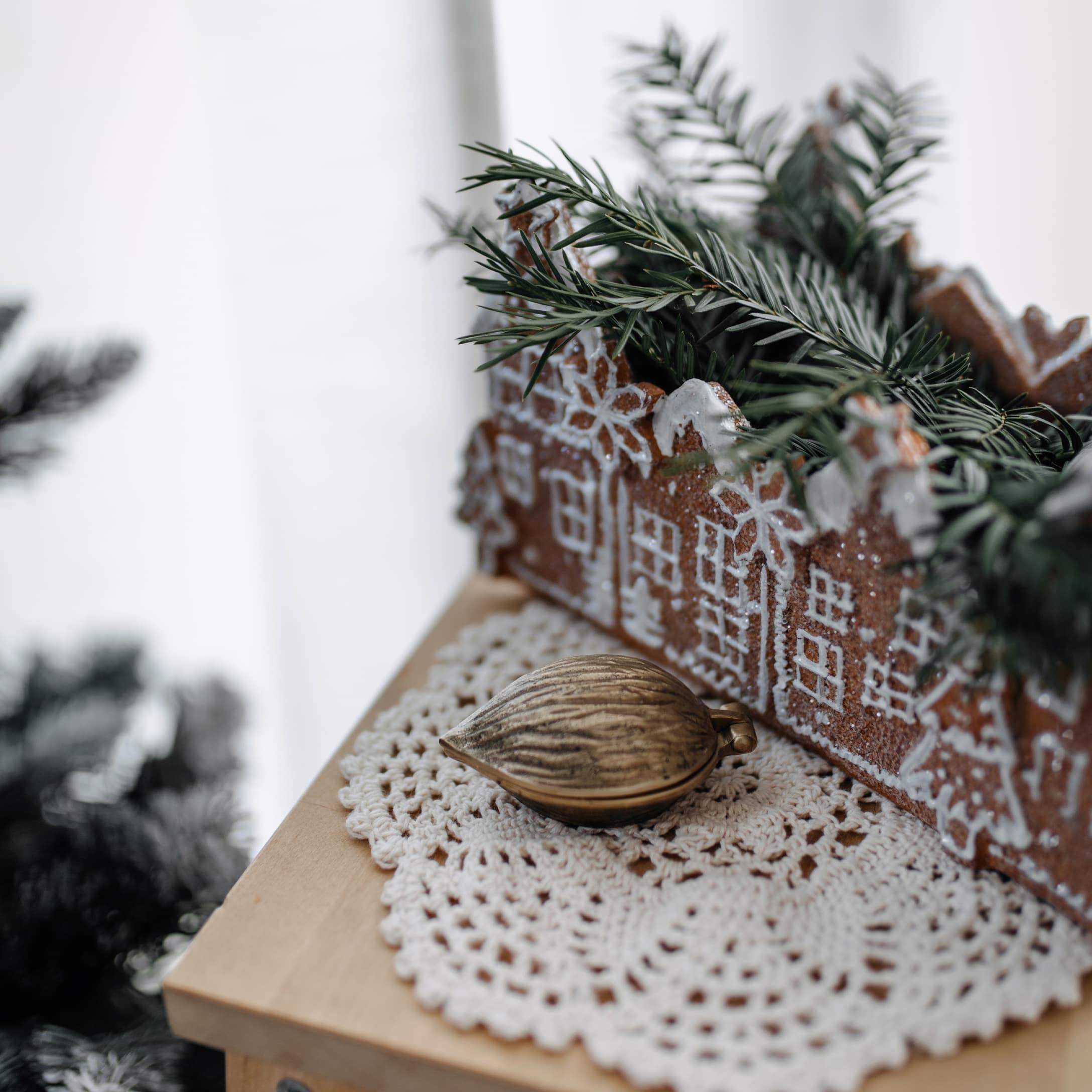 Cache-pot en céramique en forme de maison avec branches vertes sur napperon au crochet