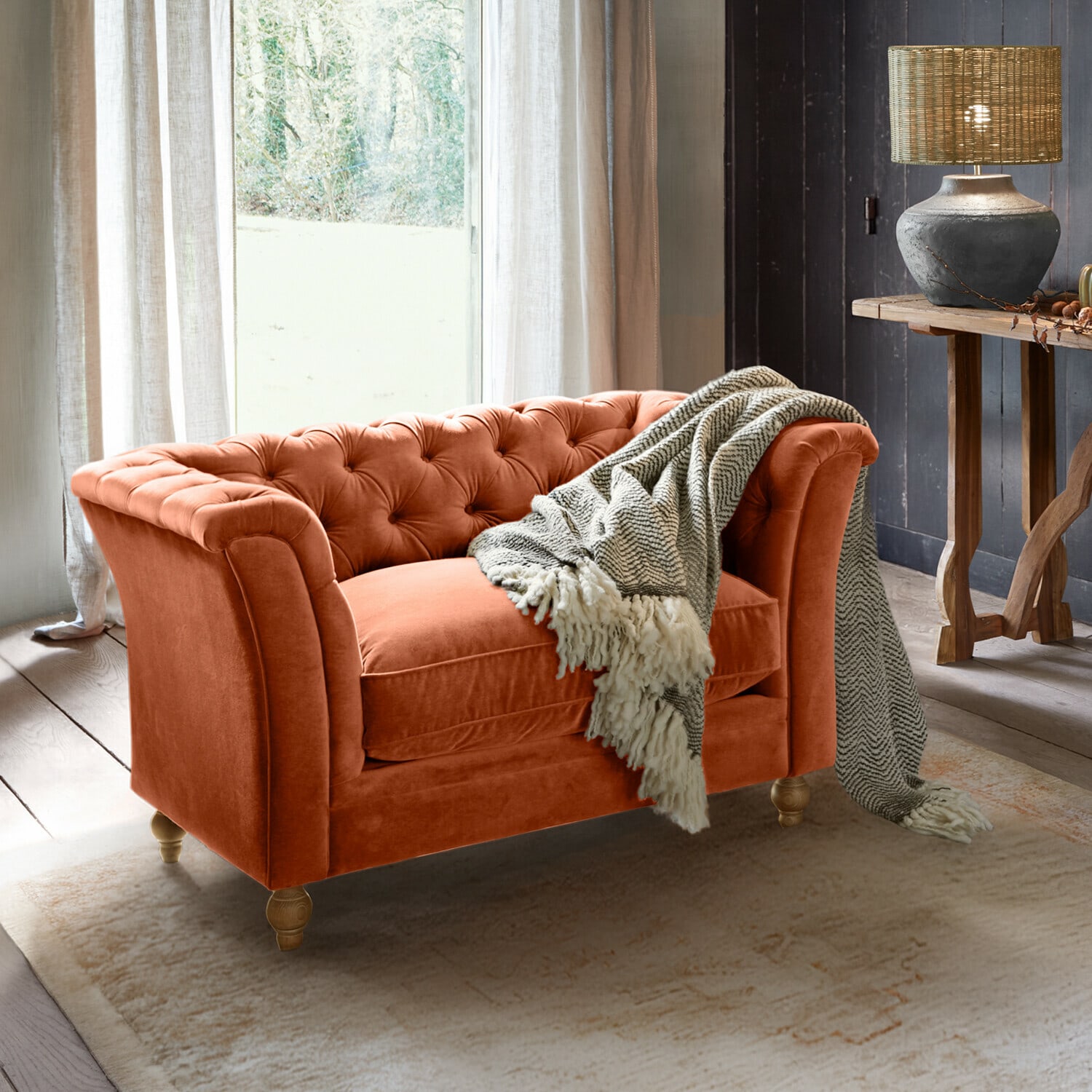 Bank Clères Oranje fluwelen Chesterfield-bank met grijze deken in gezellige woonkamer met lamp en houten tafel