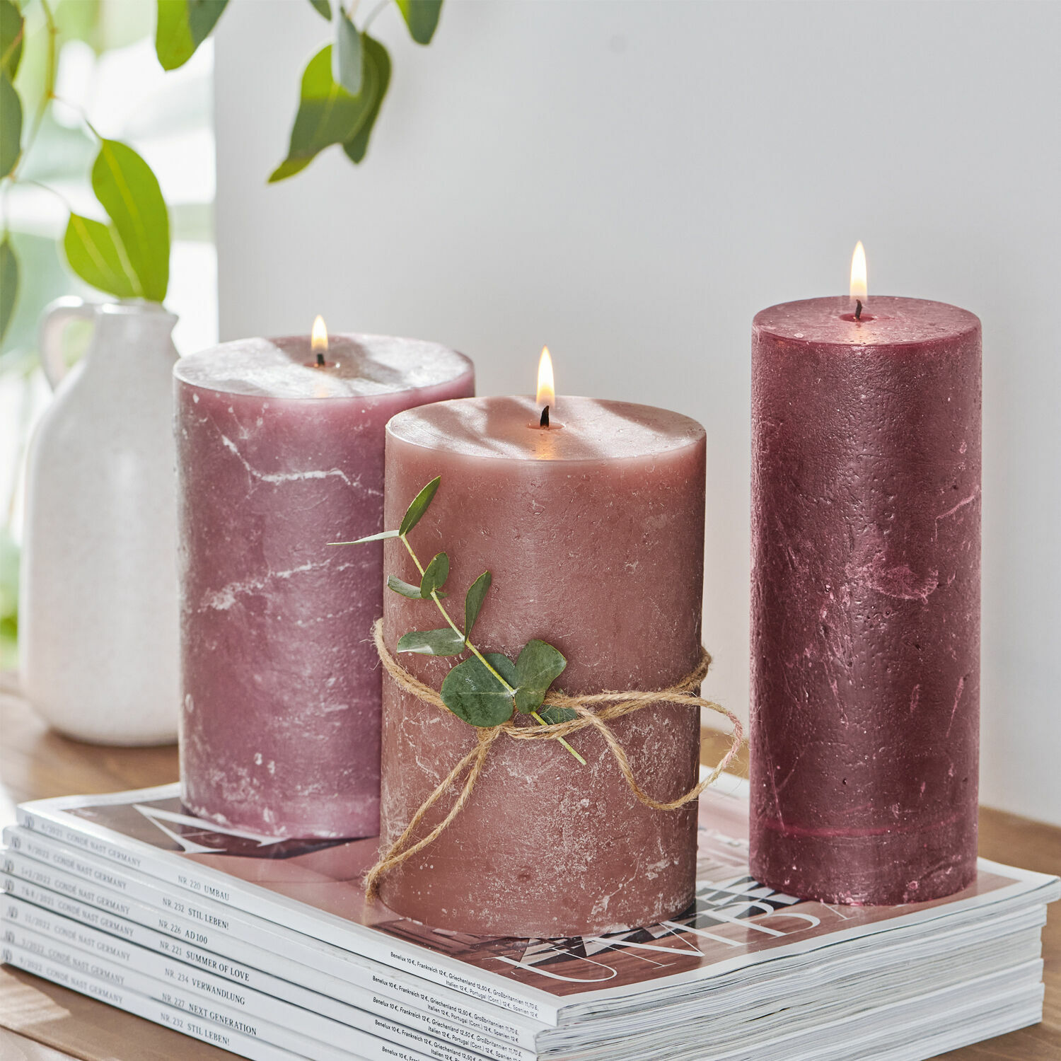 Kaars set van 3 Salis Drie roze kaarsen van was met groen blad op een stapel tijdschriften, interieurdecoratie