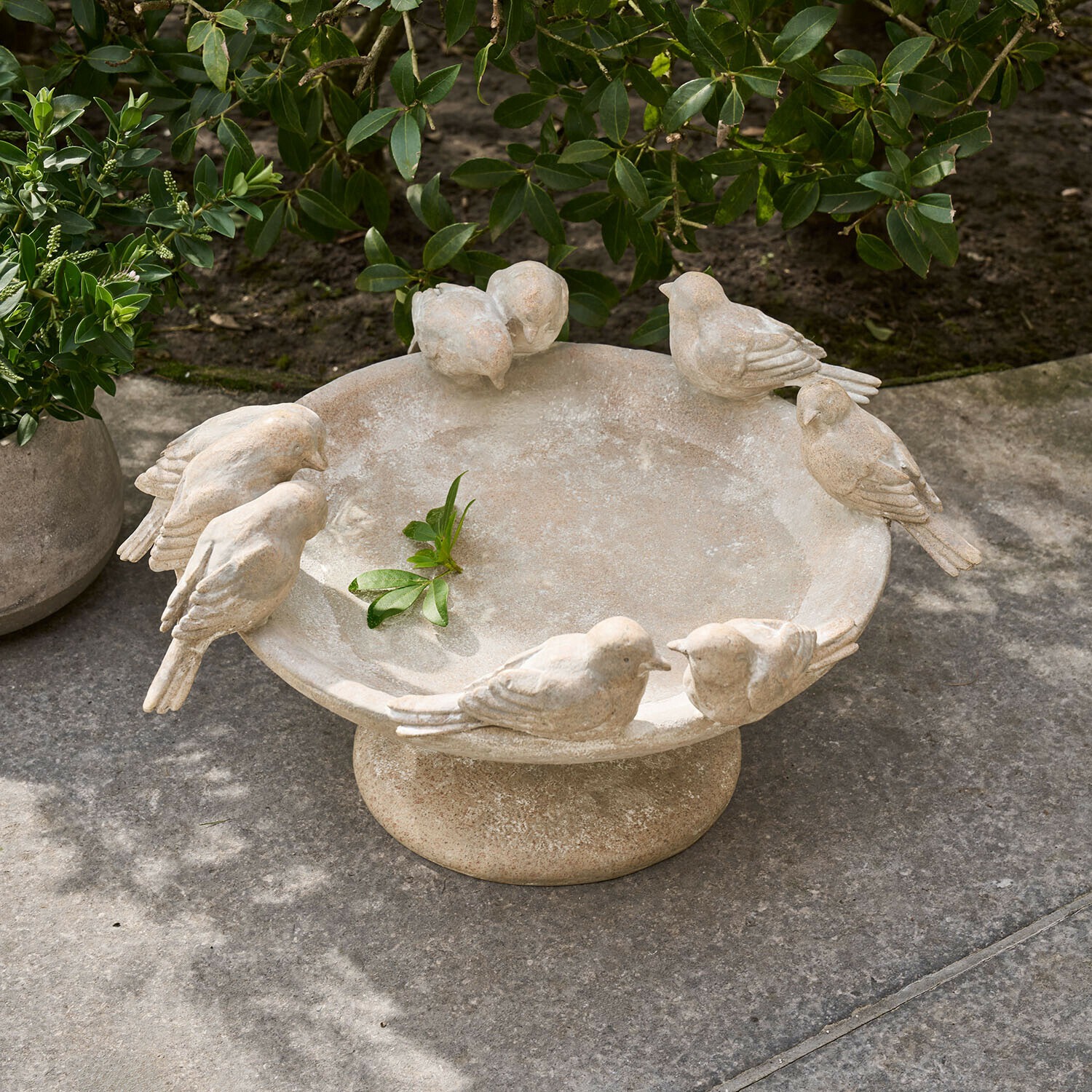 Bain d'oiseaux en pierre beige avec oiseaux sculptés, décor de jardin élégant et naturel