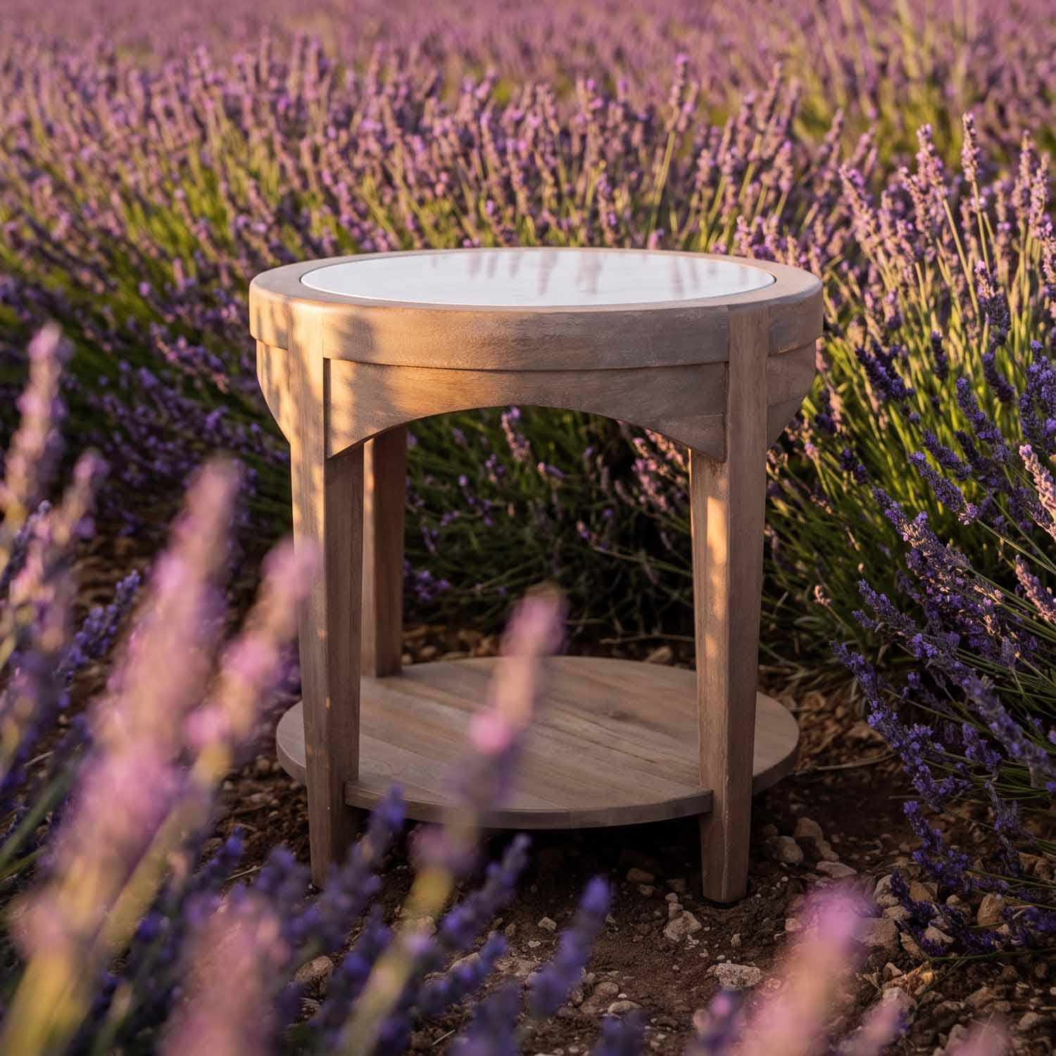 Ronde houten tafel met wit blad, geplaatst tussen paarse lavendelbloemen buiten