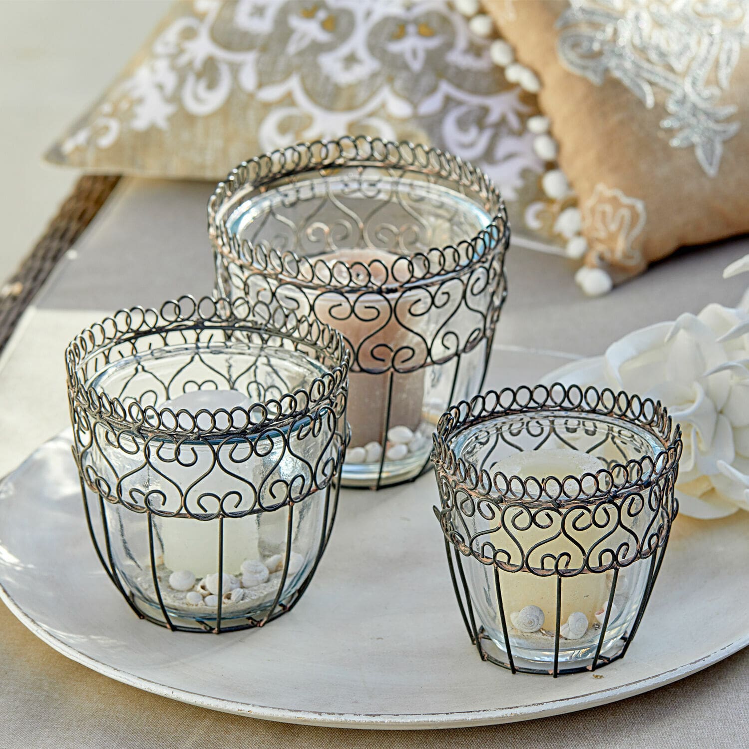 Ensemble de trois photophores en verre avec cadre métallique noir orné de motifs décoratifs sur un plateau