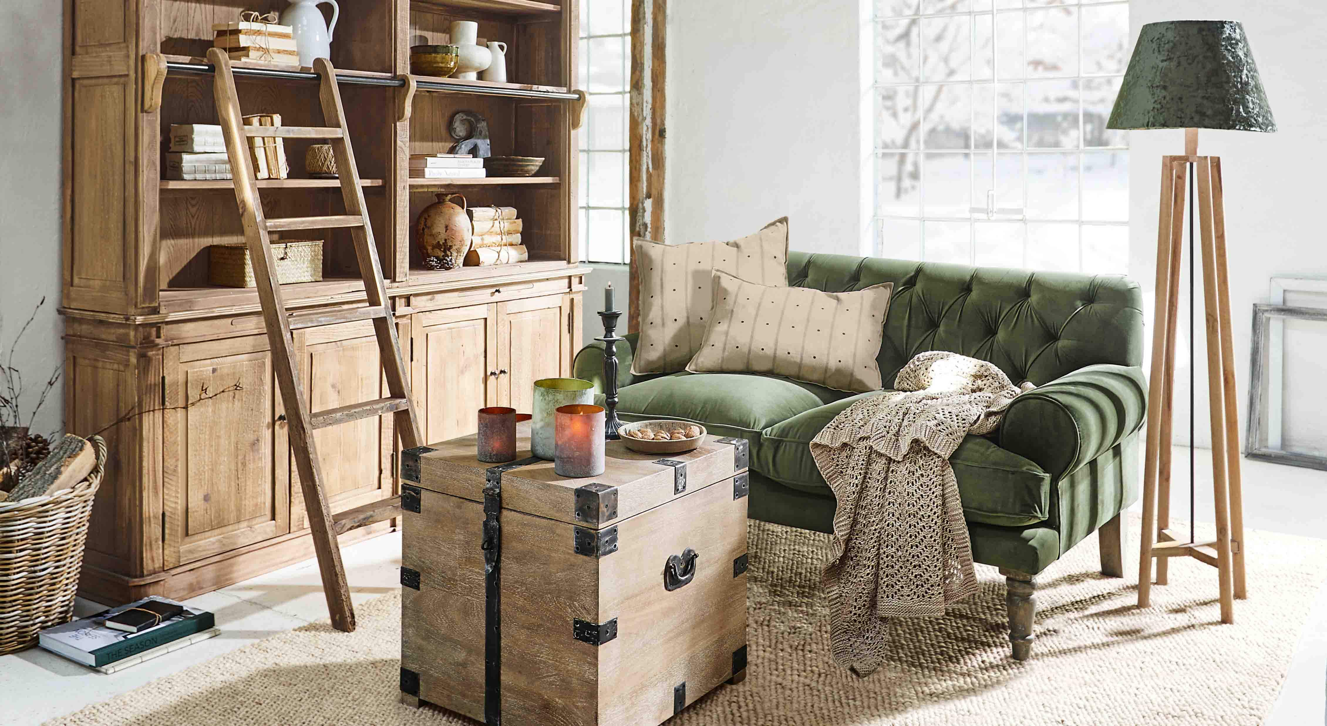 Gezellige woonkamer met groene fluwelen bank, houten kast en vloerlamp van natuurlijk hout