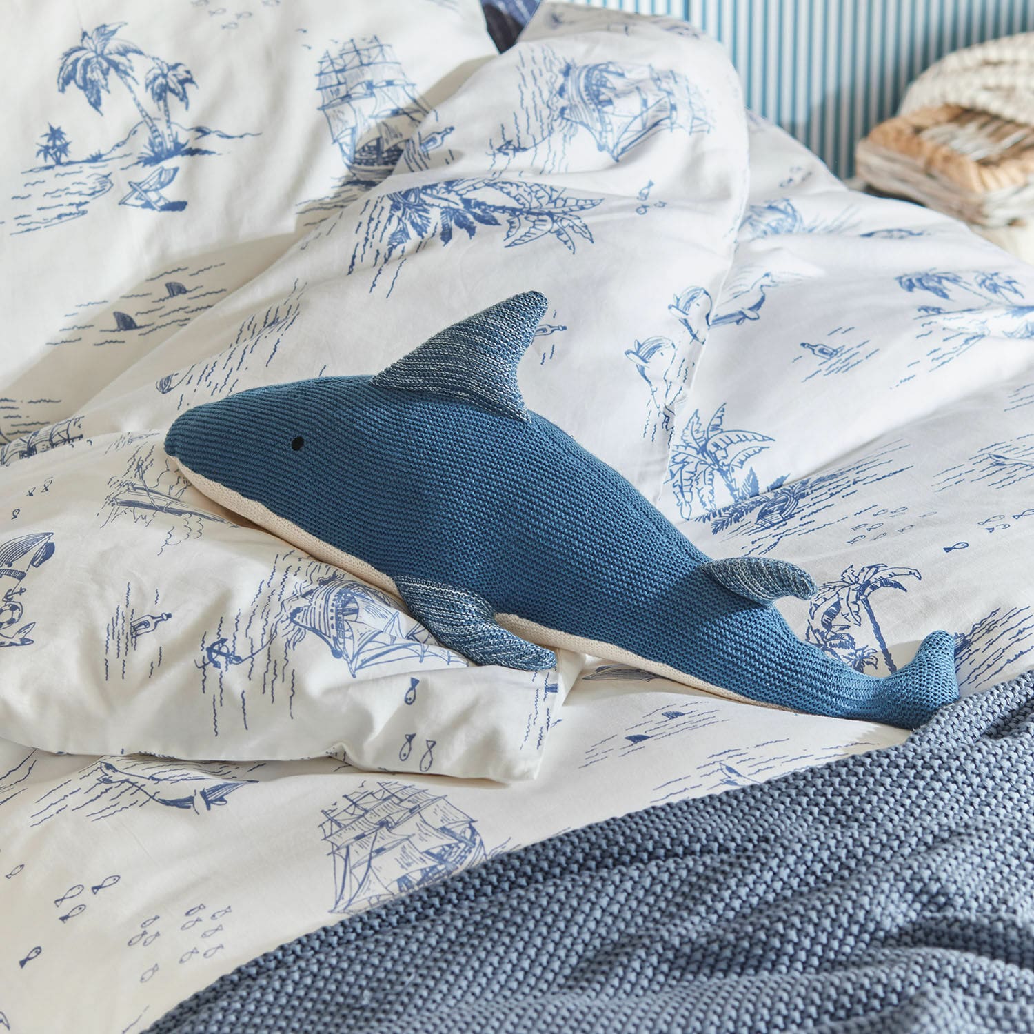 Knuffeldier Cheruboo Blauwe gebreide haai kussen op wit beddengoed met blauwe maritieme motieven