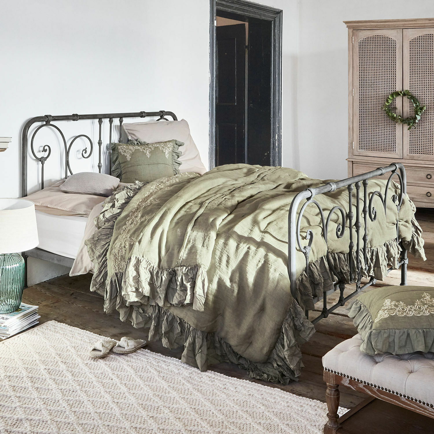 Bed Genouillé Metalen bed met groene linnen beddengoed met ruches in rustieke slaapkamer