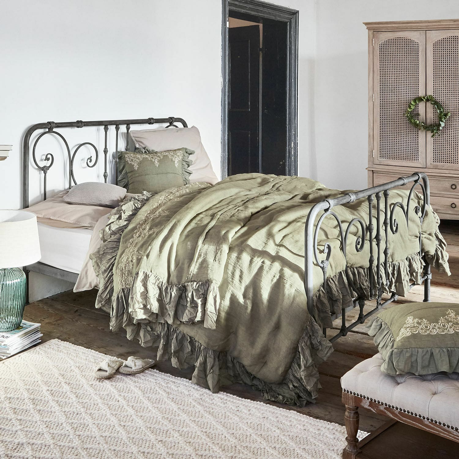 Bed Genouillé Metalen bed met groene linnen beddengoed met ruches in rustieke slaapkamer