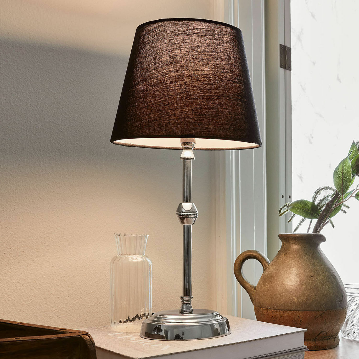 Tafellamp Luceau Elegante tafellamp met metalen voet en zwarte kap op bureau met decoratie