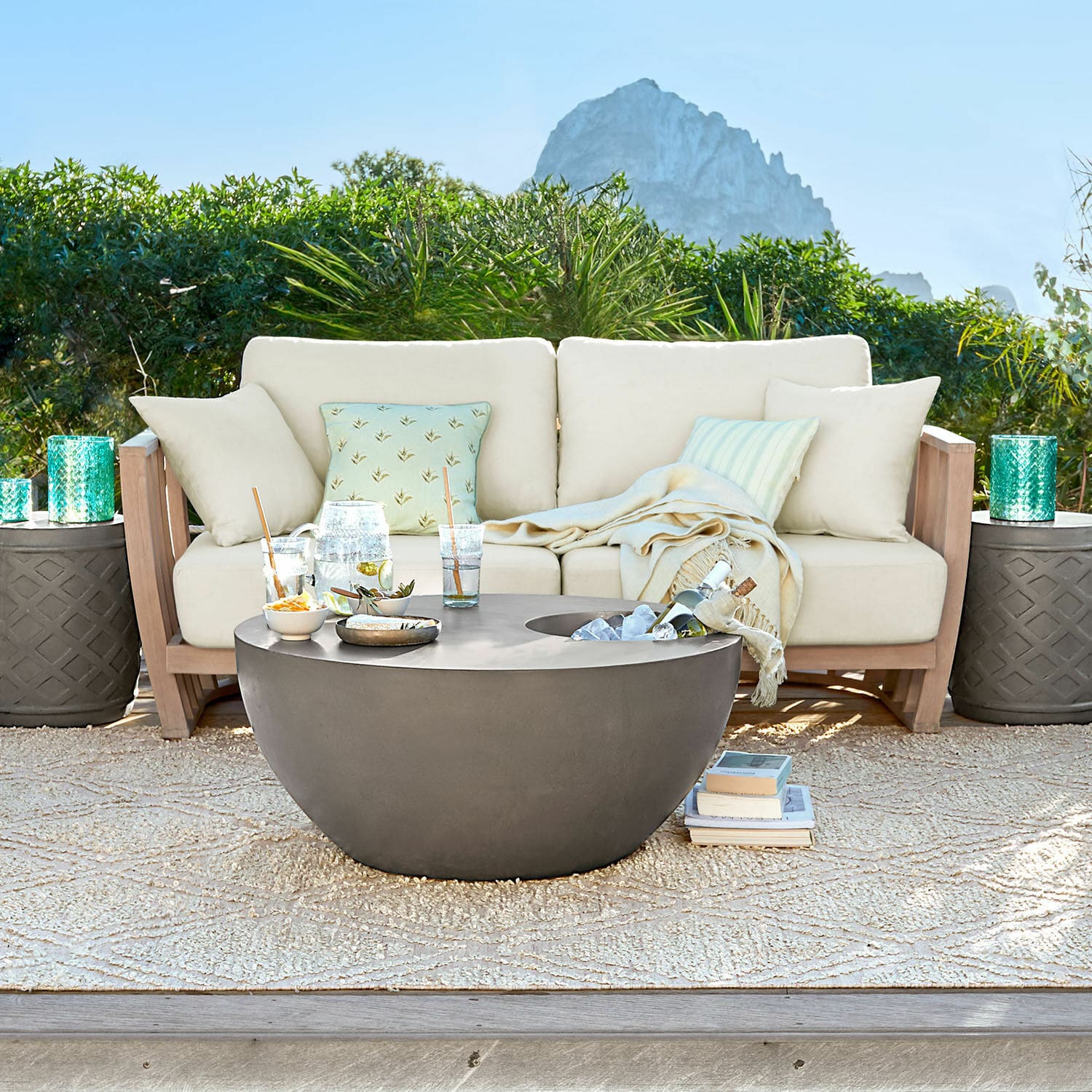 Canapé FSC®-100% Vézère Table basse ronde en béton gris moderne sur terrasse avec canapé beige et coussins décoratifs