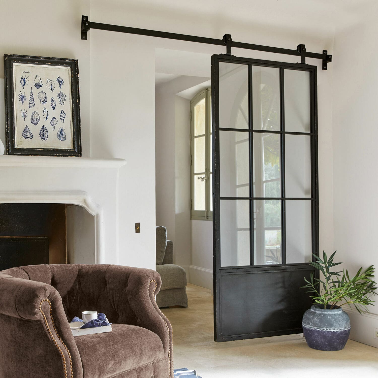 Porte coulissante Luisant Porte coulissante loft en métal noir et verre dans un intérieur moderne avec fauteuil et cheminée