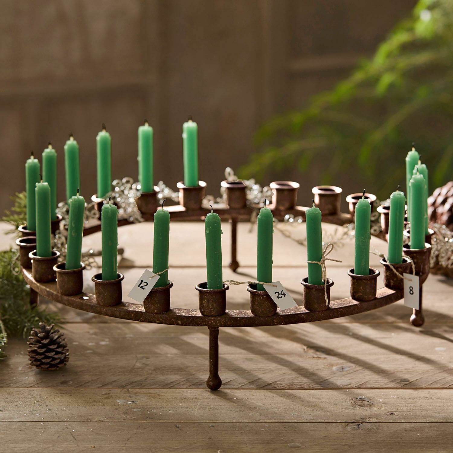 Chandelier en métal rustique avec bougies vertes numérotées sur une table en bois