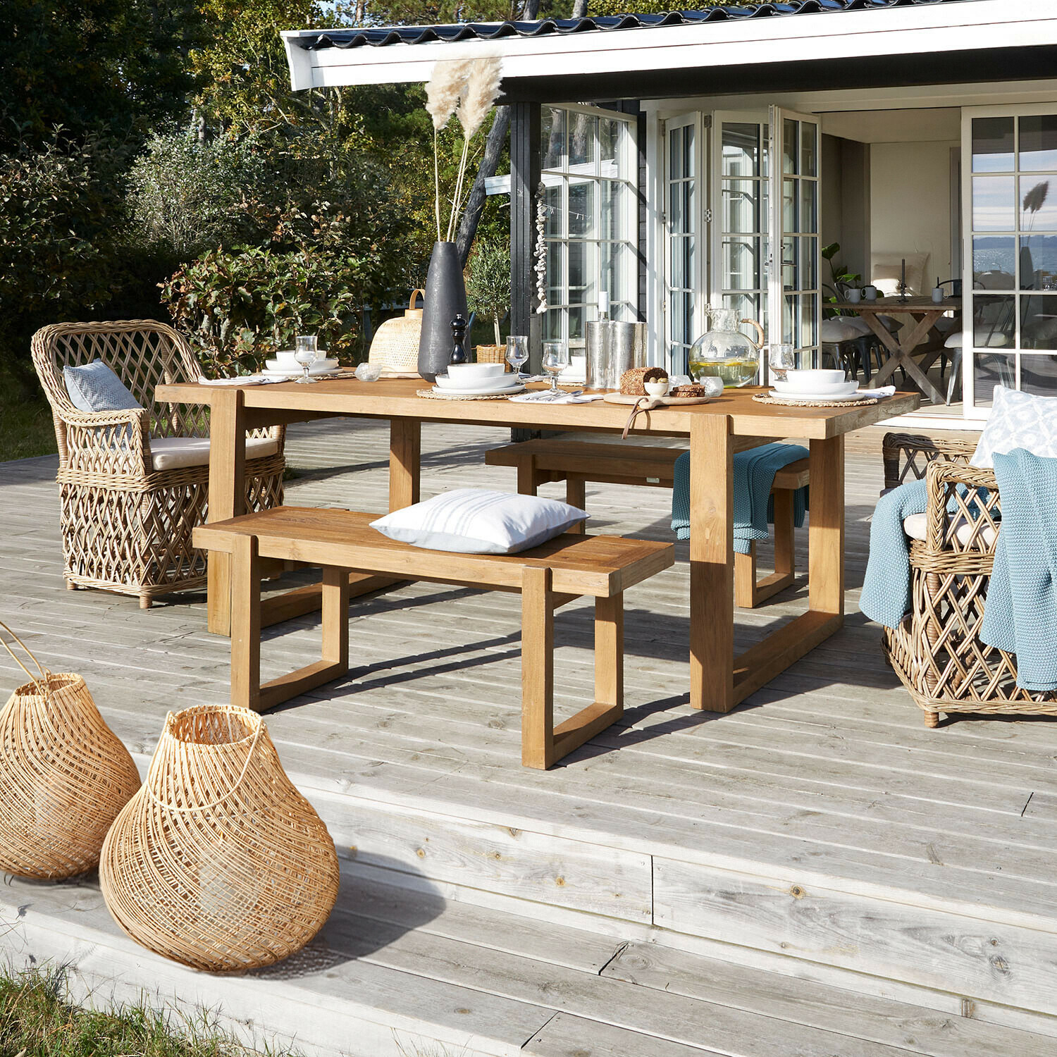 Banc Halinor Table de jardin en bois avec bancs et fauteuils en osier sur terrasse en bois avec décorations naturelles