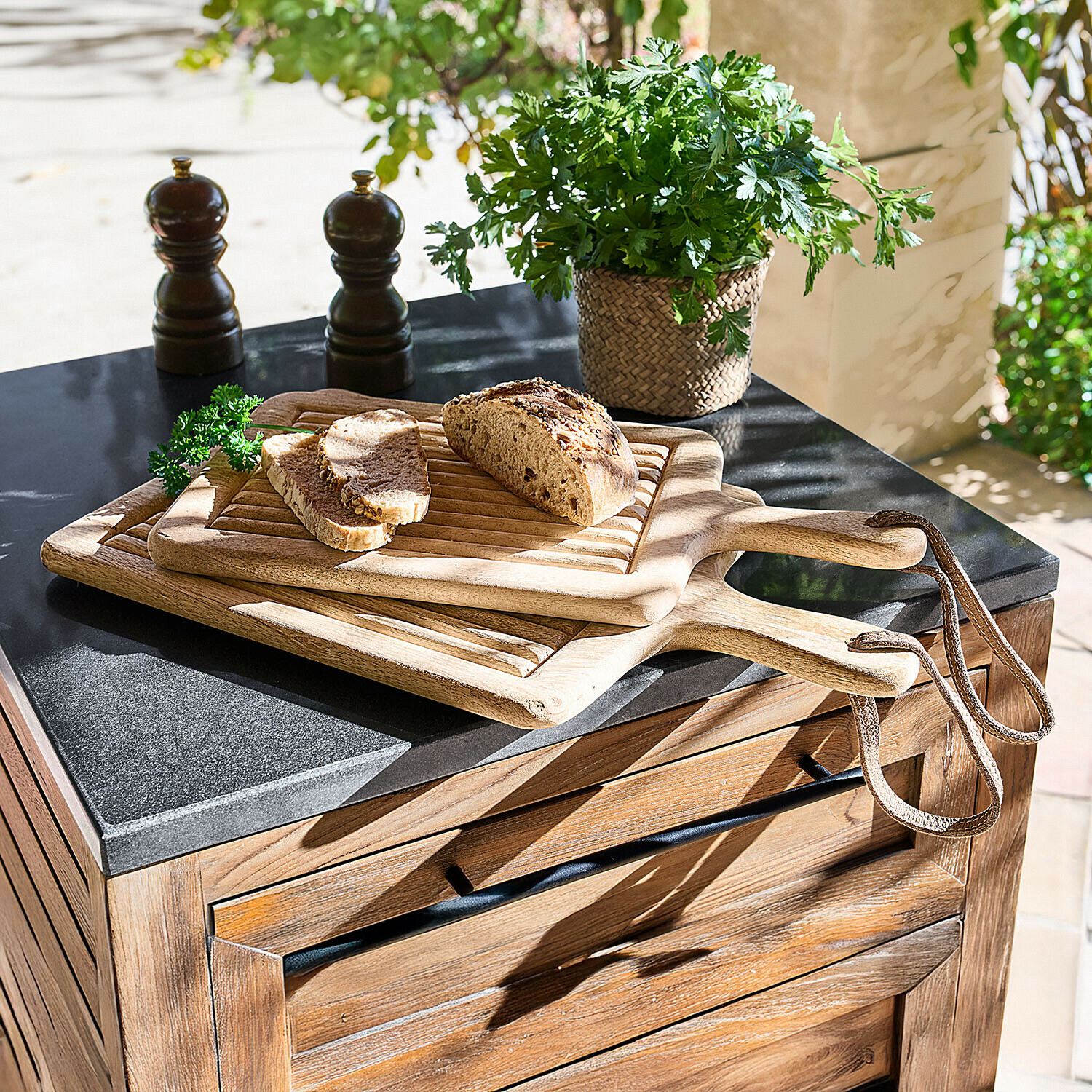 Snijplank set van 2 Vianzo Drie houten snijplanken met handvat en lus, met brood en verse kruiden op een keukenblad