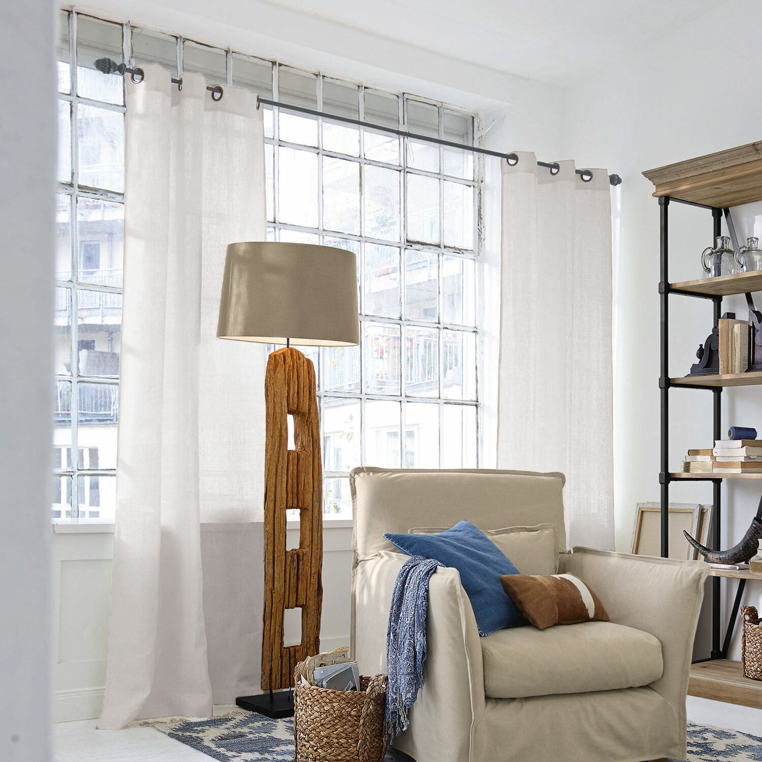 Rideau Salinas Lampadaire en bois avec abat-jour beige dans un salon lumineux avec fauteuil et étagère