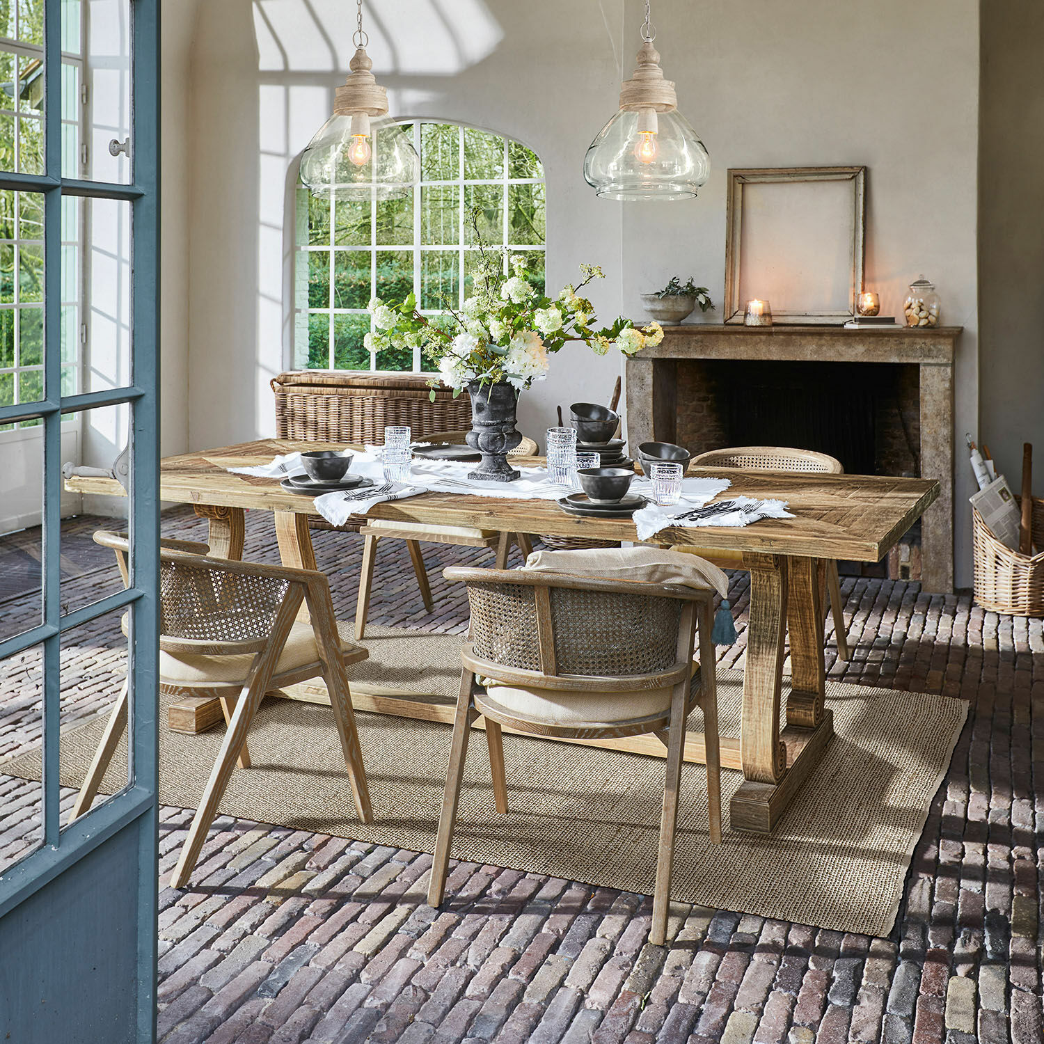 Tafel Campbelltown Eetkamer met houten tafel en rieten stoelen op bakstenen vloer met bloemendecoratie