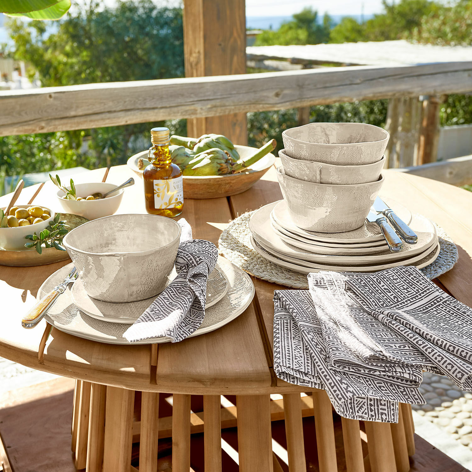 Servies set van 12 Luganville Beige keramiek servies set met kommen en borden op houten tafel buiten
